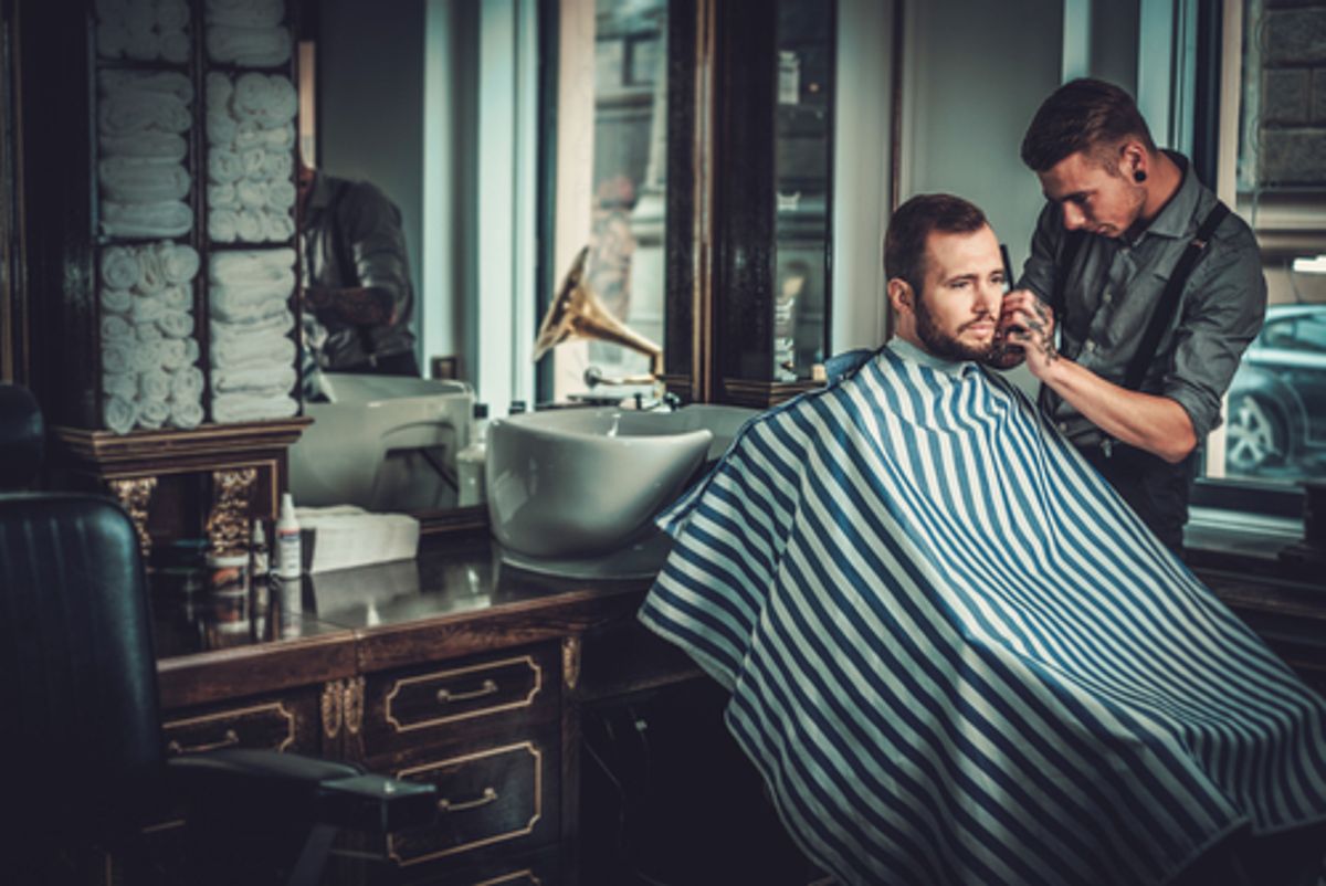 Barber focused on trimming client's beard.