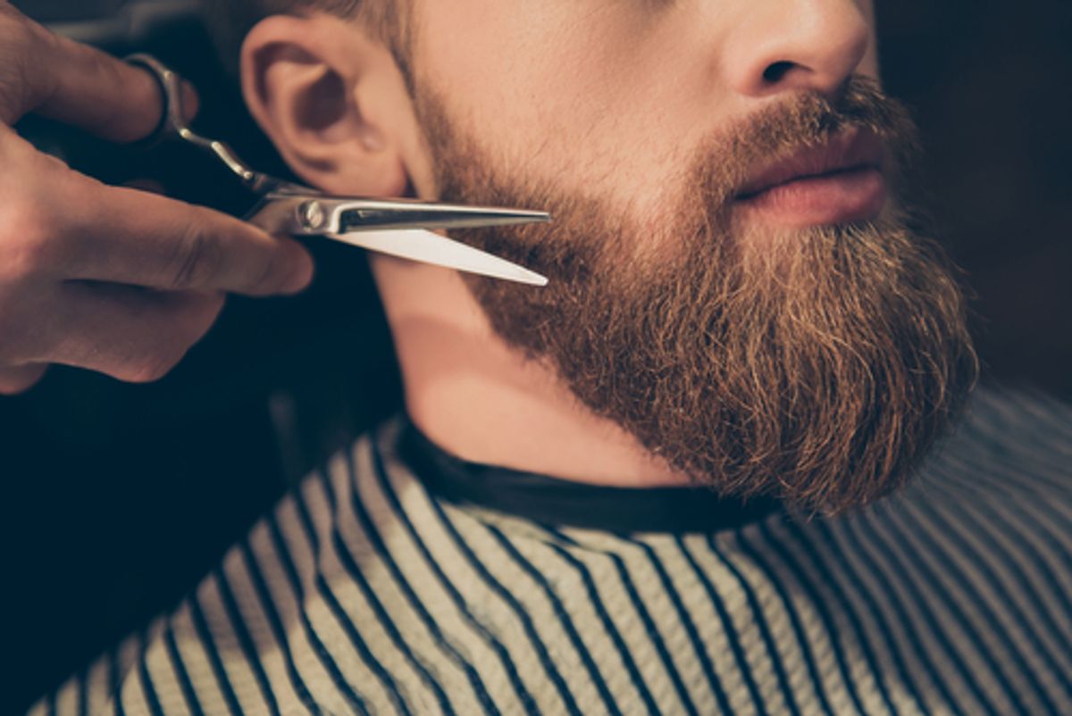 Barber trimming a beard with scissors.