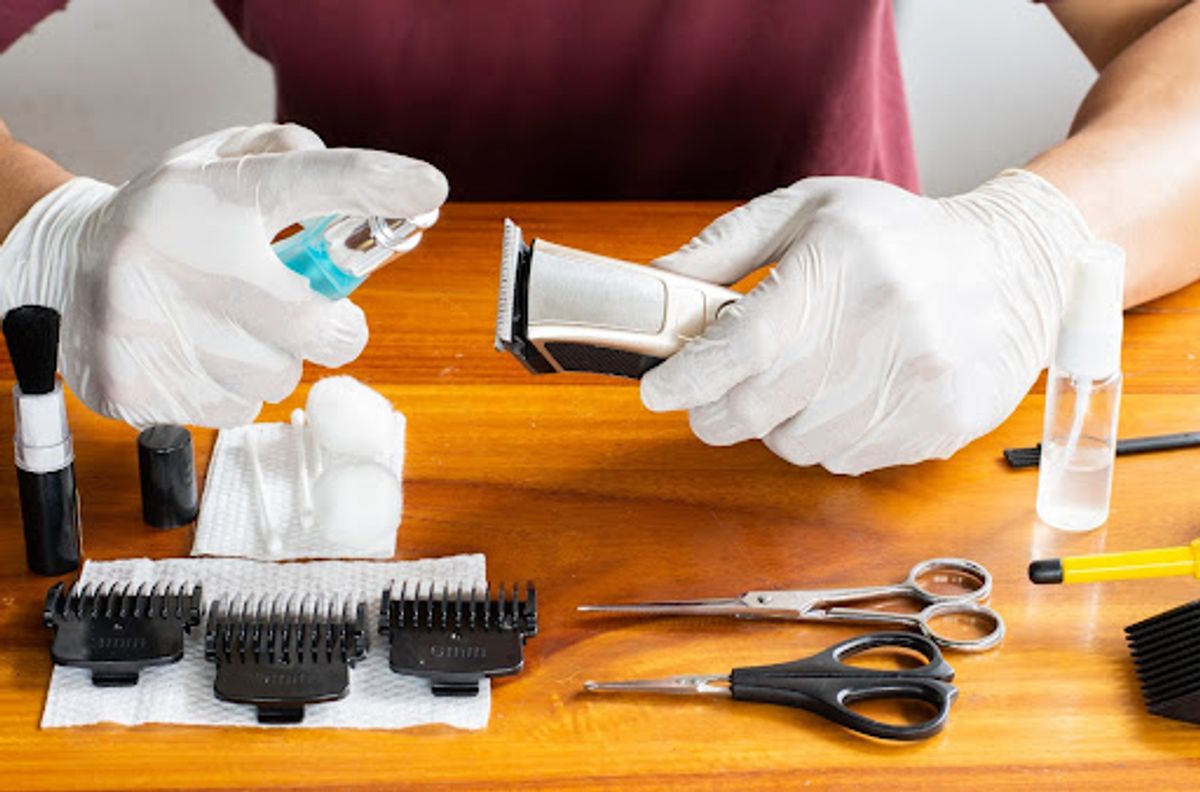 Person sanitizing hair clippers with Barbicide.