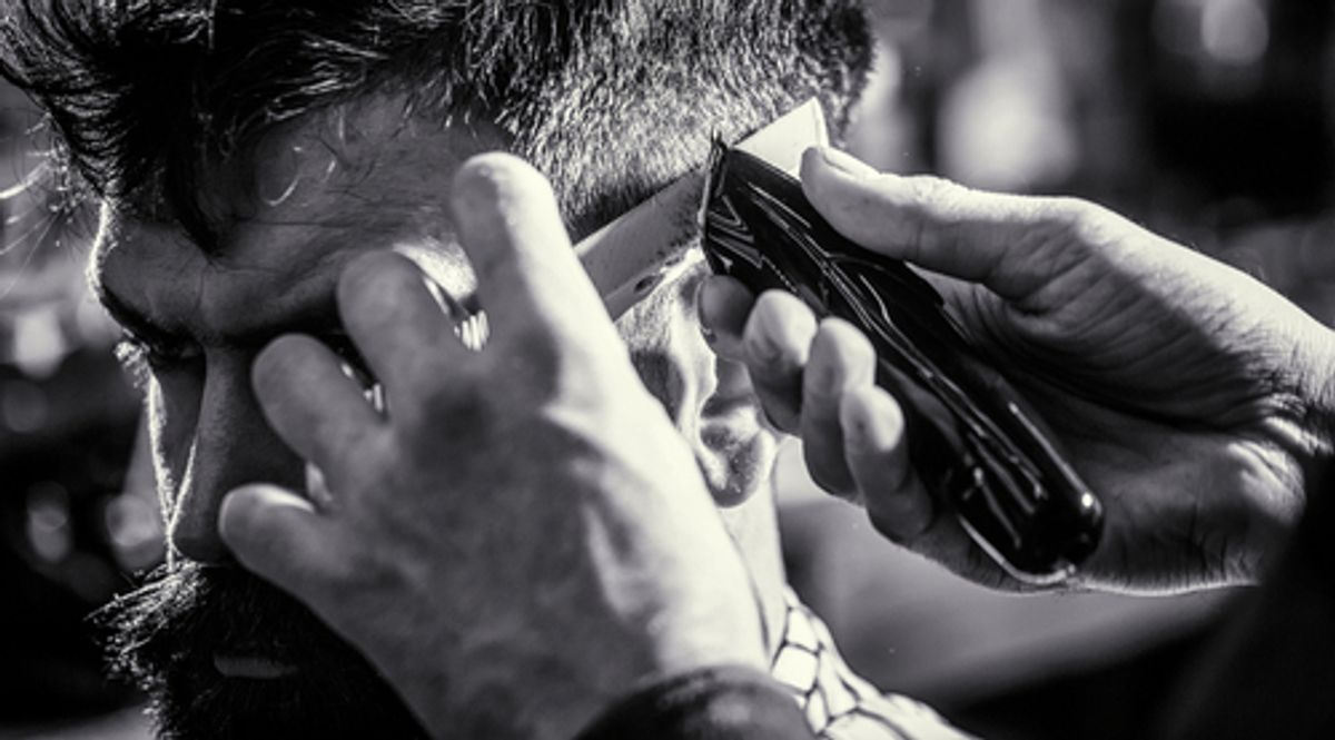 Barber trimming hair with clippers.