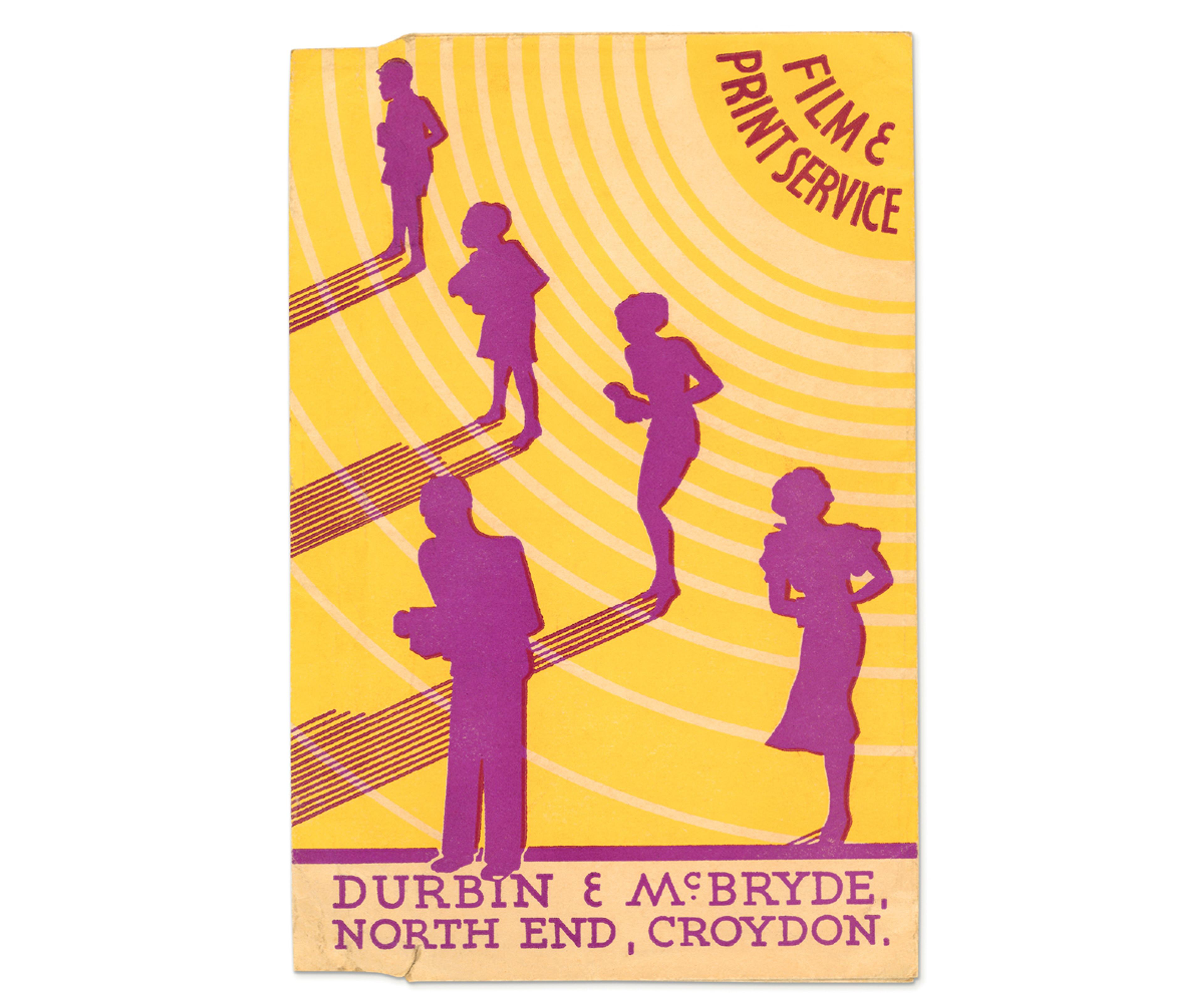 Photograph of a bright yellow photo wallet, with the silhouettes of five people with cameras in their hands, with their backs to the sun and the text 'Film & Print Service' and at the bottom the text 'Durbin & McBryde, North End, Croydon.