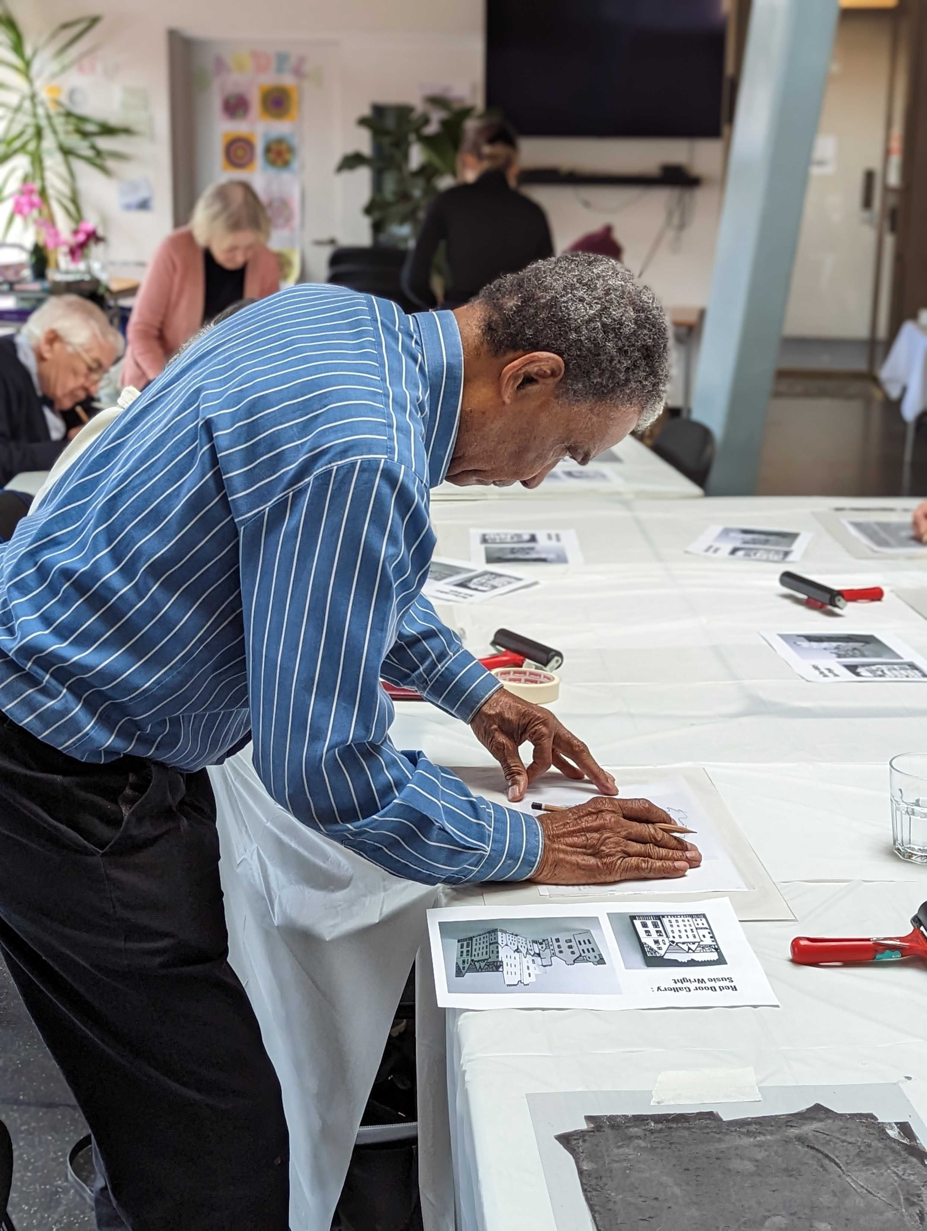 Person leaning over a table lining up a piece of paper on top of a table.