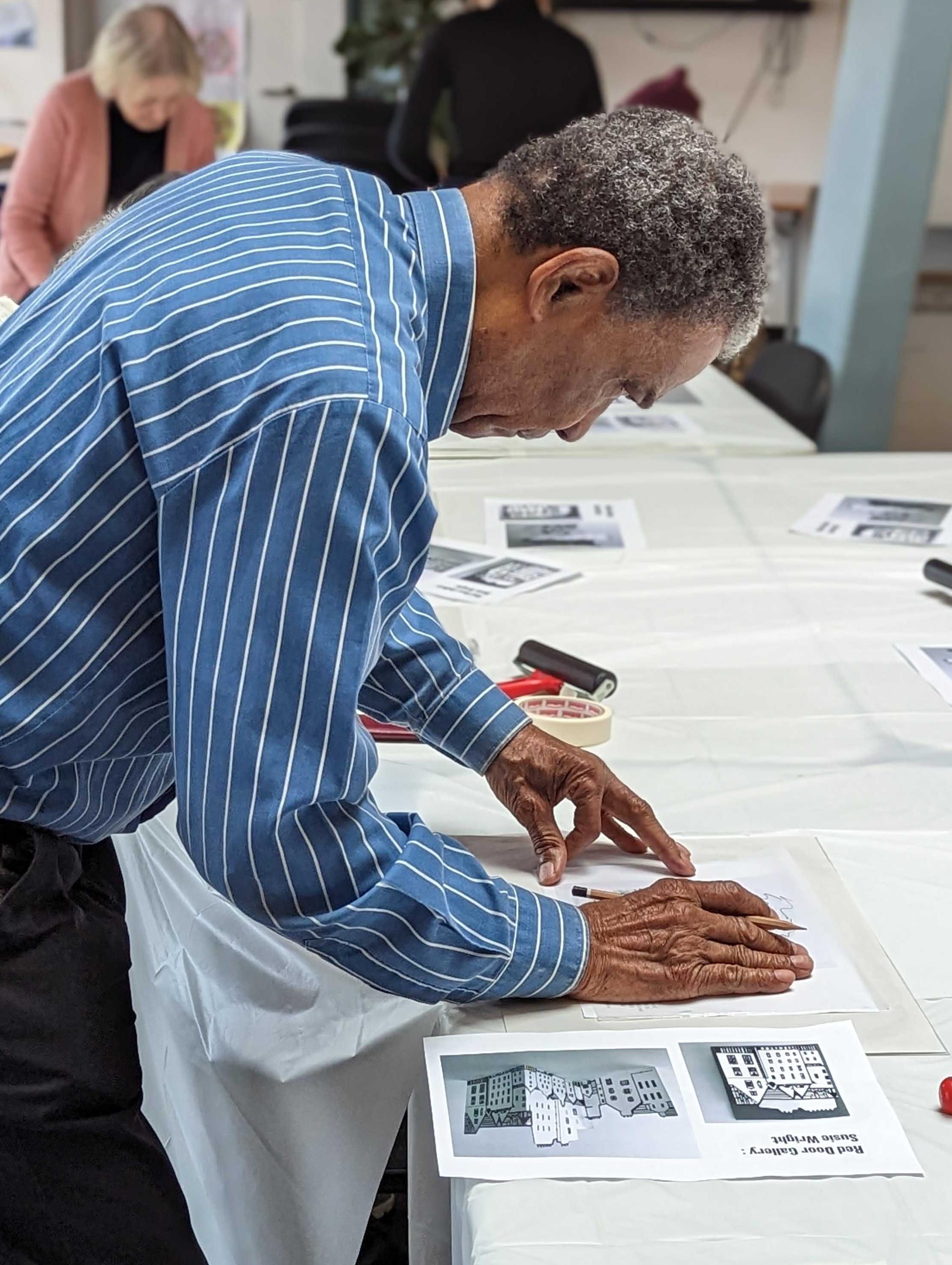 Person leaning over a table lining up a piece of paper on top of a table.