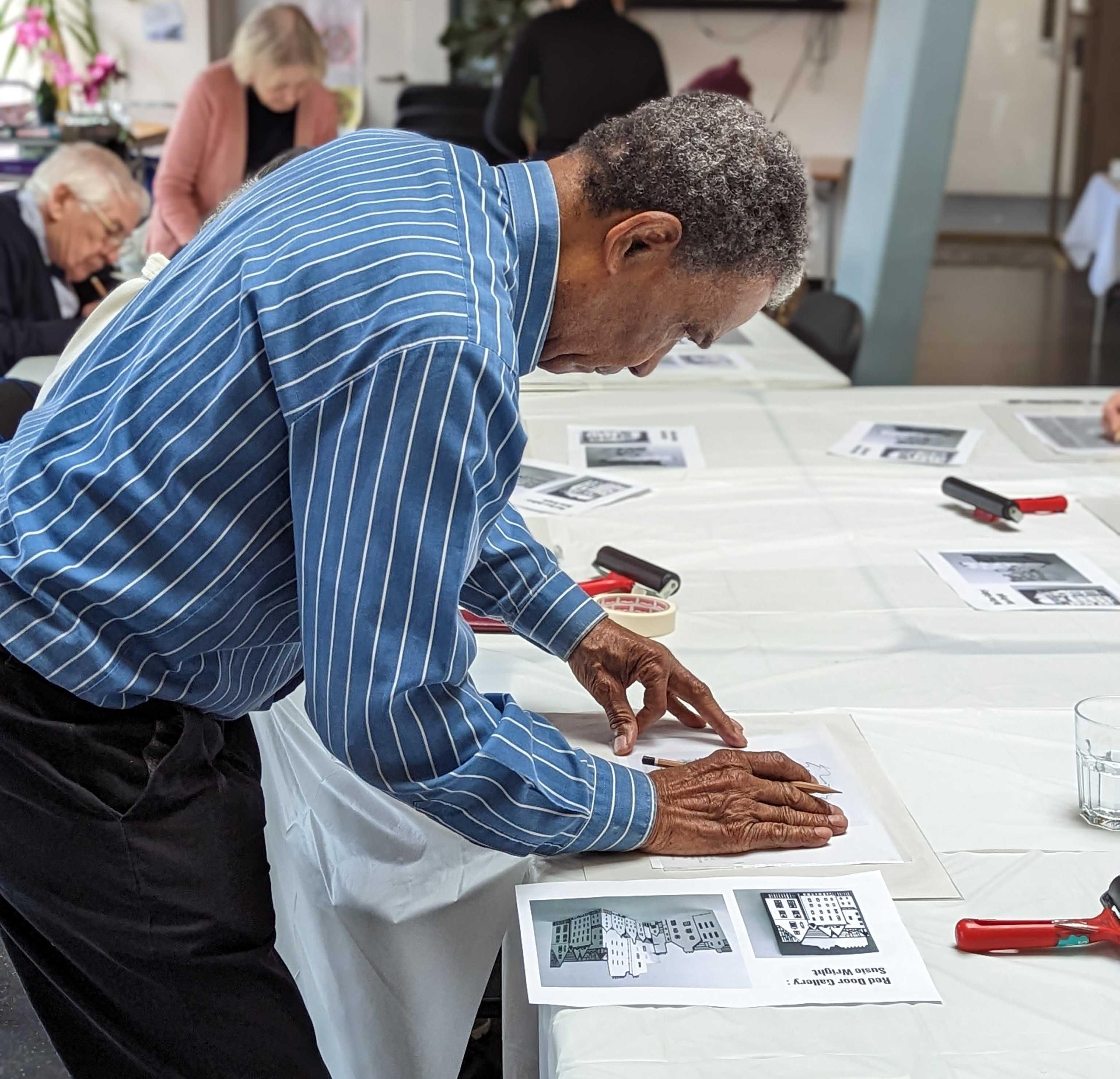 Person leaning over a table lining up a piece of paper on top of a table.