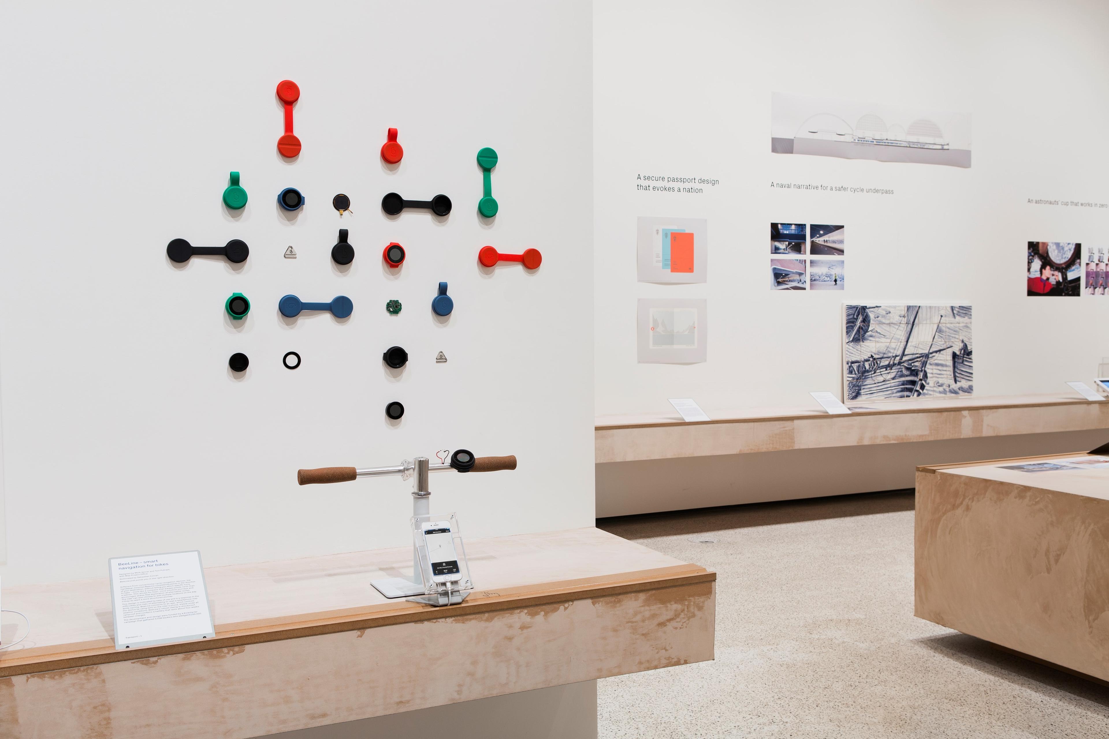 A photograph of a gallery in the Design Museum. Colourful objects are displayed on plaster coloured counters and white walls.