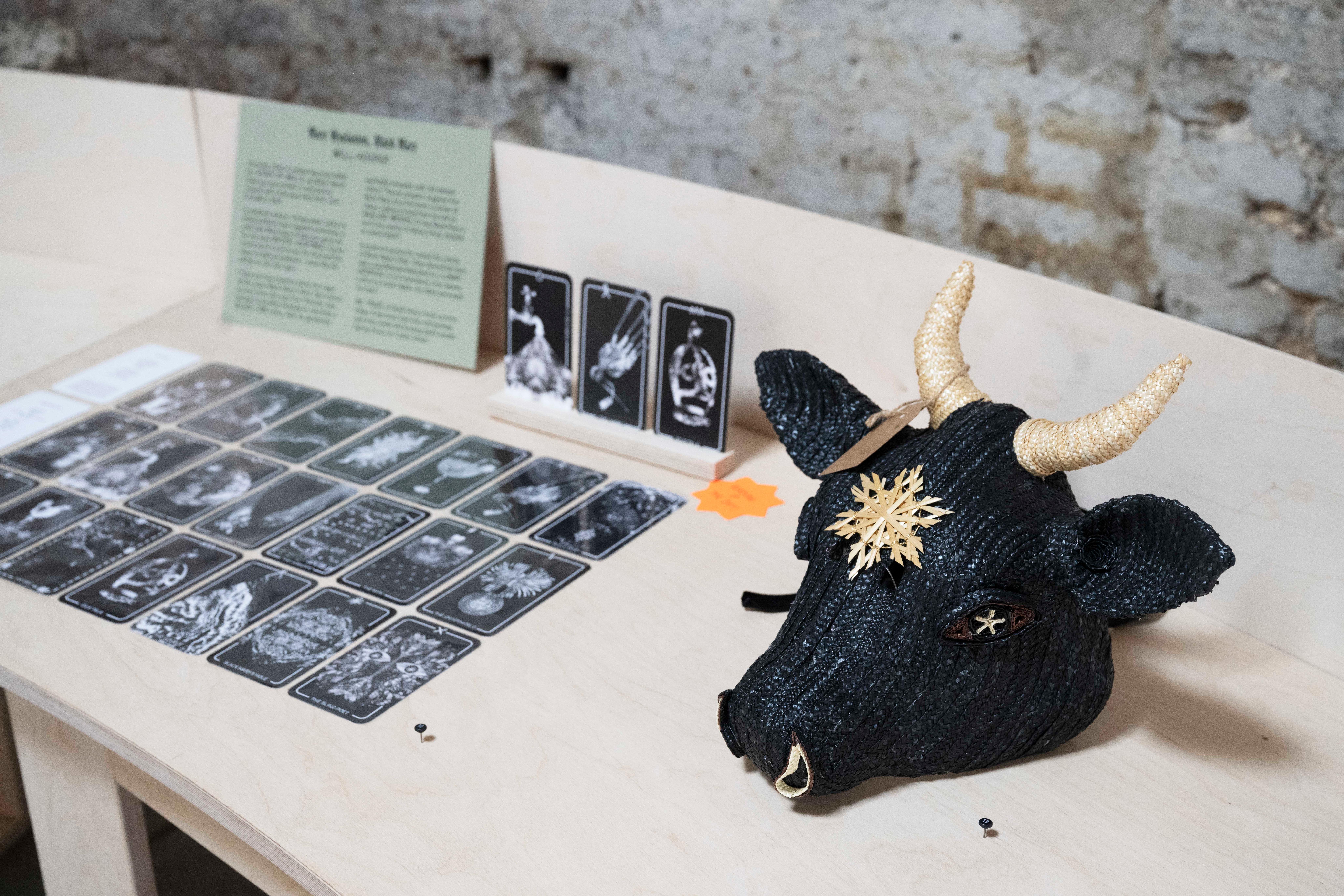 Photograph of a woven mask and tarot cards on a wooden platform.