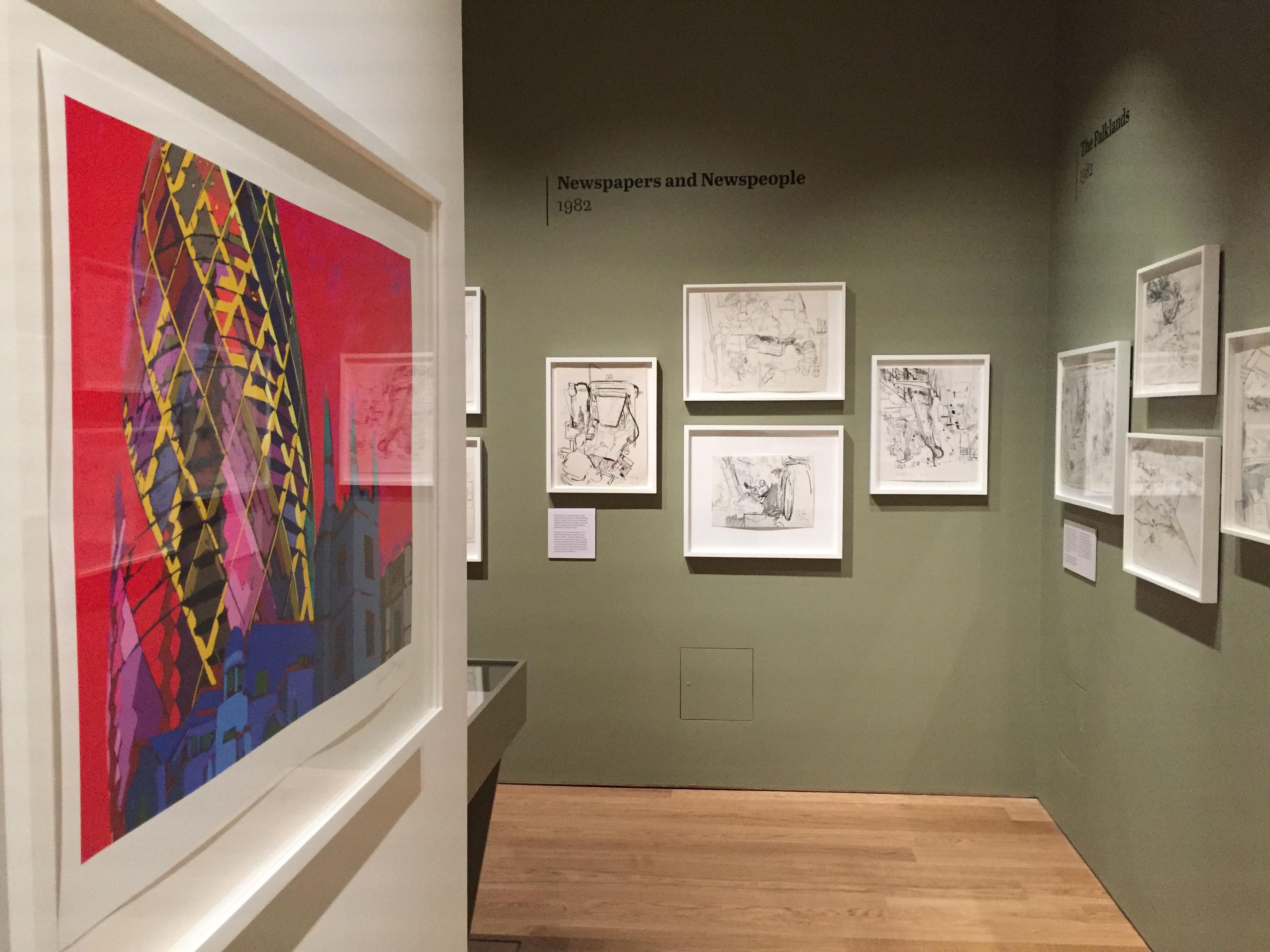 Framed illustrations displayed on a green wall in an exhibition space.