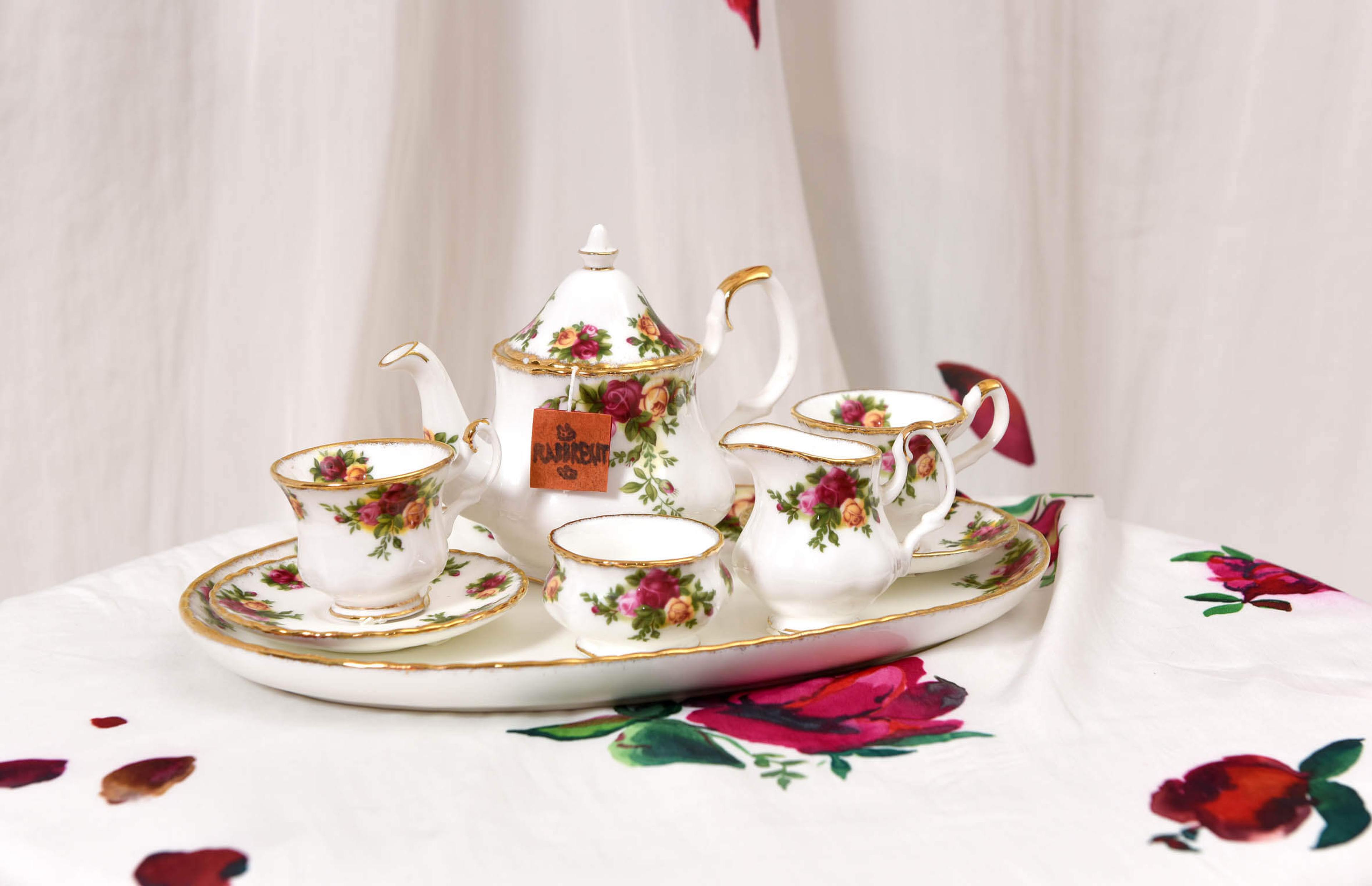 Display of an ornamental tea set arranged on a ha nd paianted table cloth hand