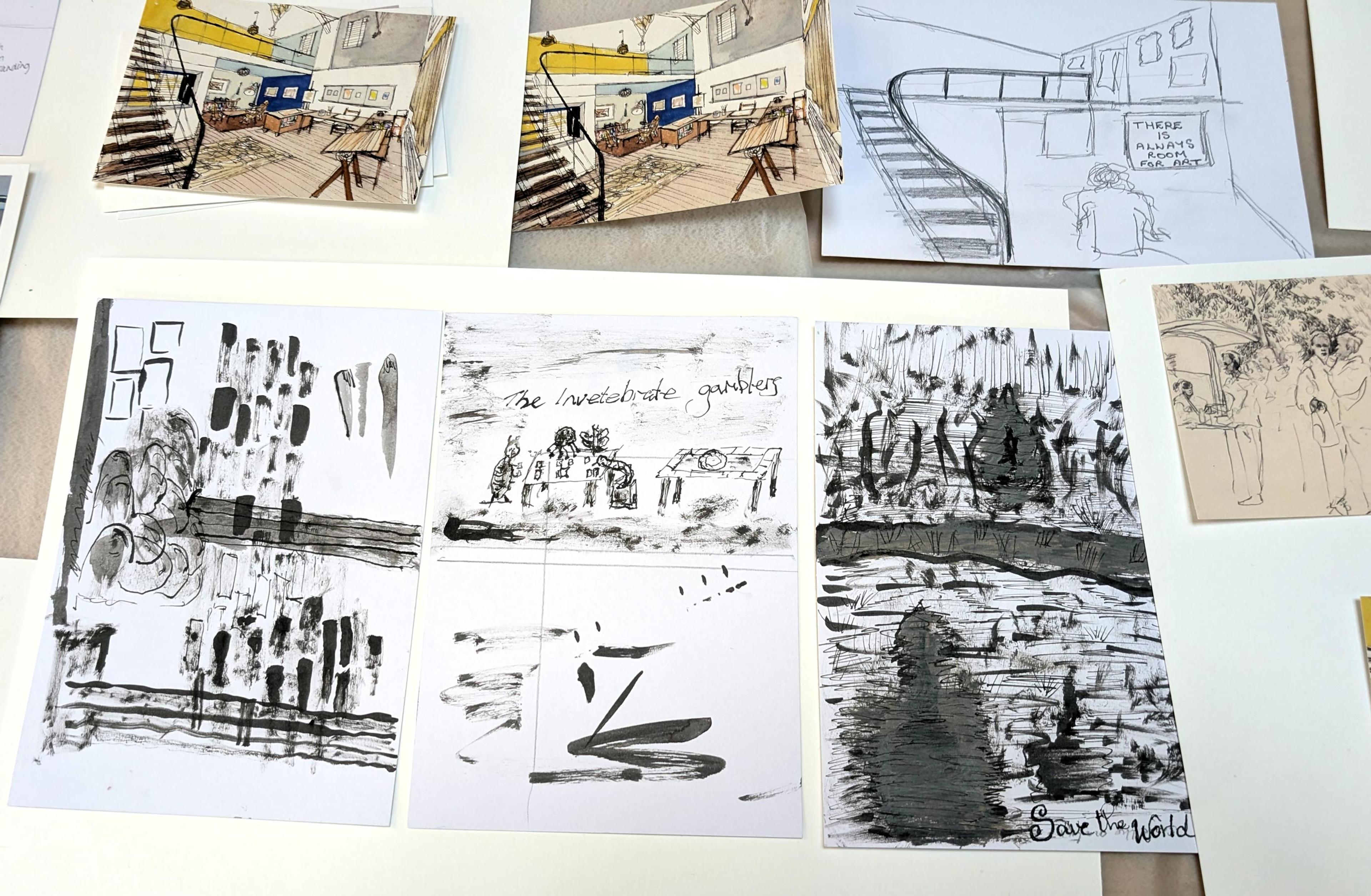 A photograph of several black and white ink drawings on a table, next to some postcards showing an illustration of an art gallery scene