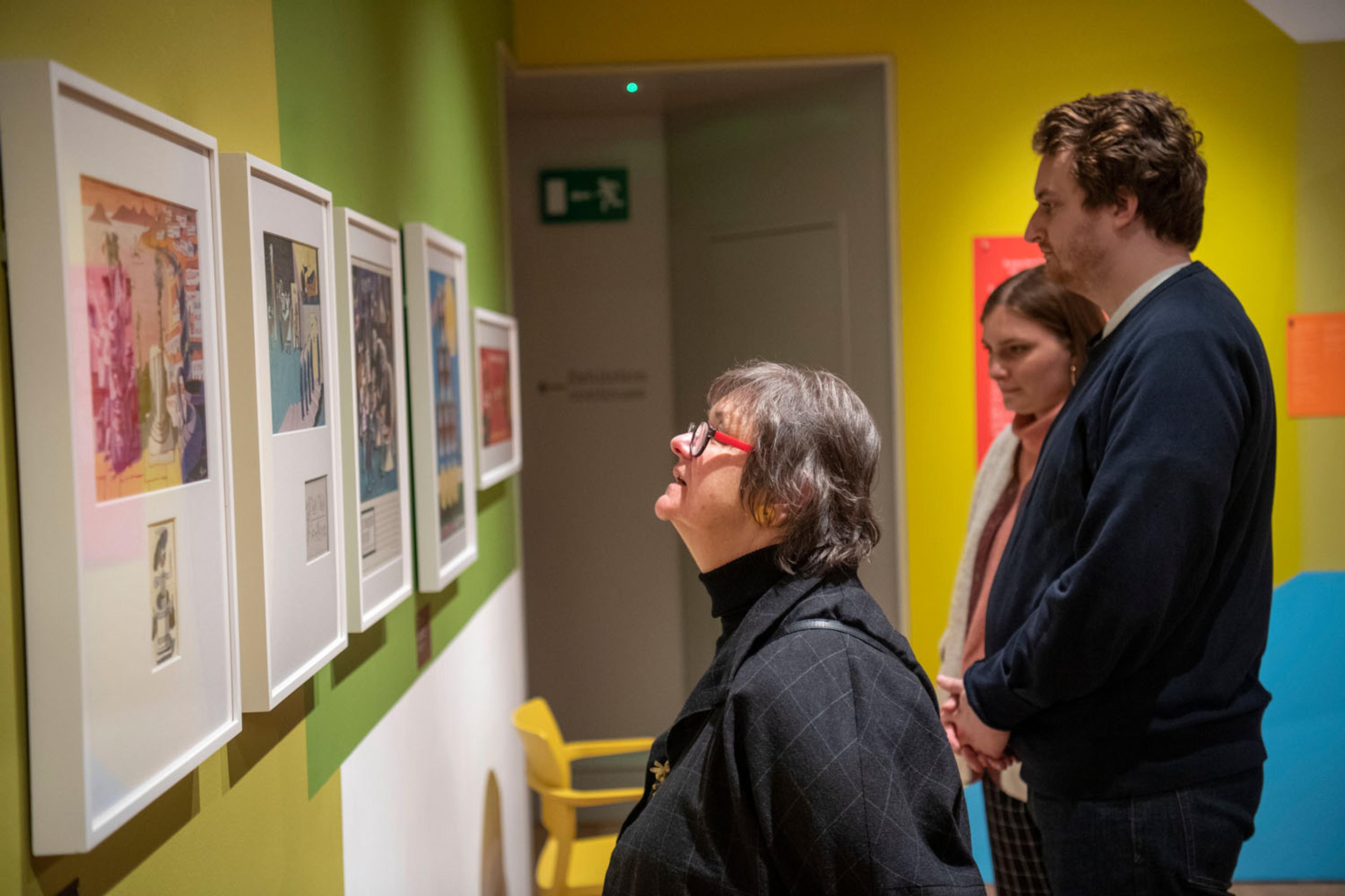 Visitors looking at artwork at the George Him exhibition