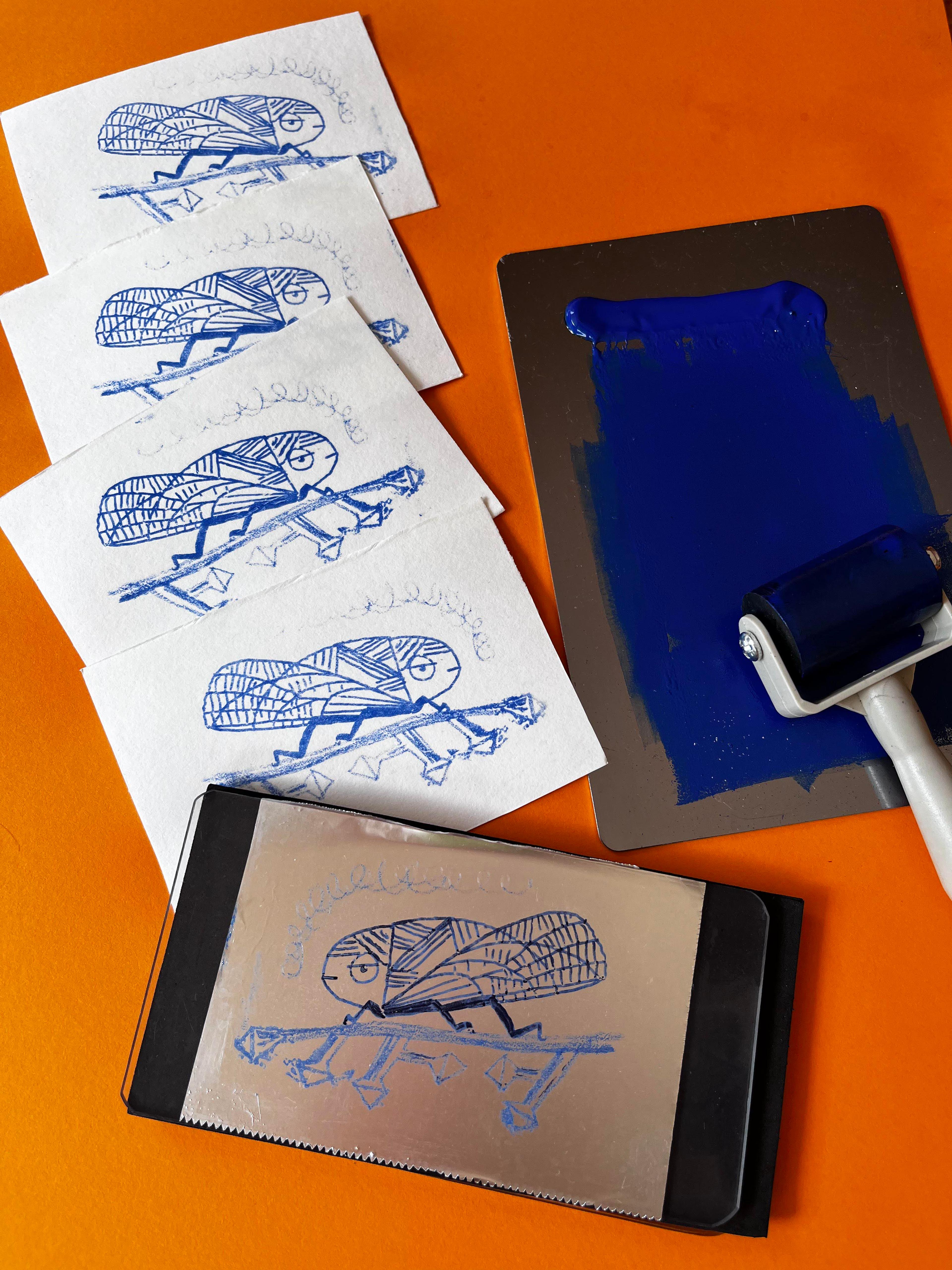 Printing copies of an insect with a roller and blue ink.