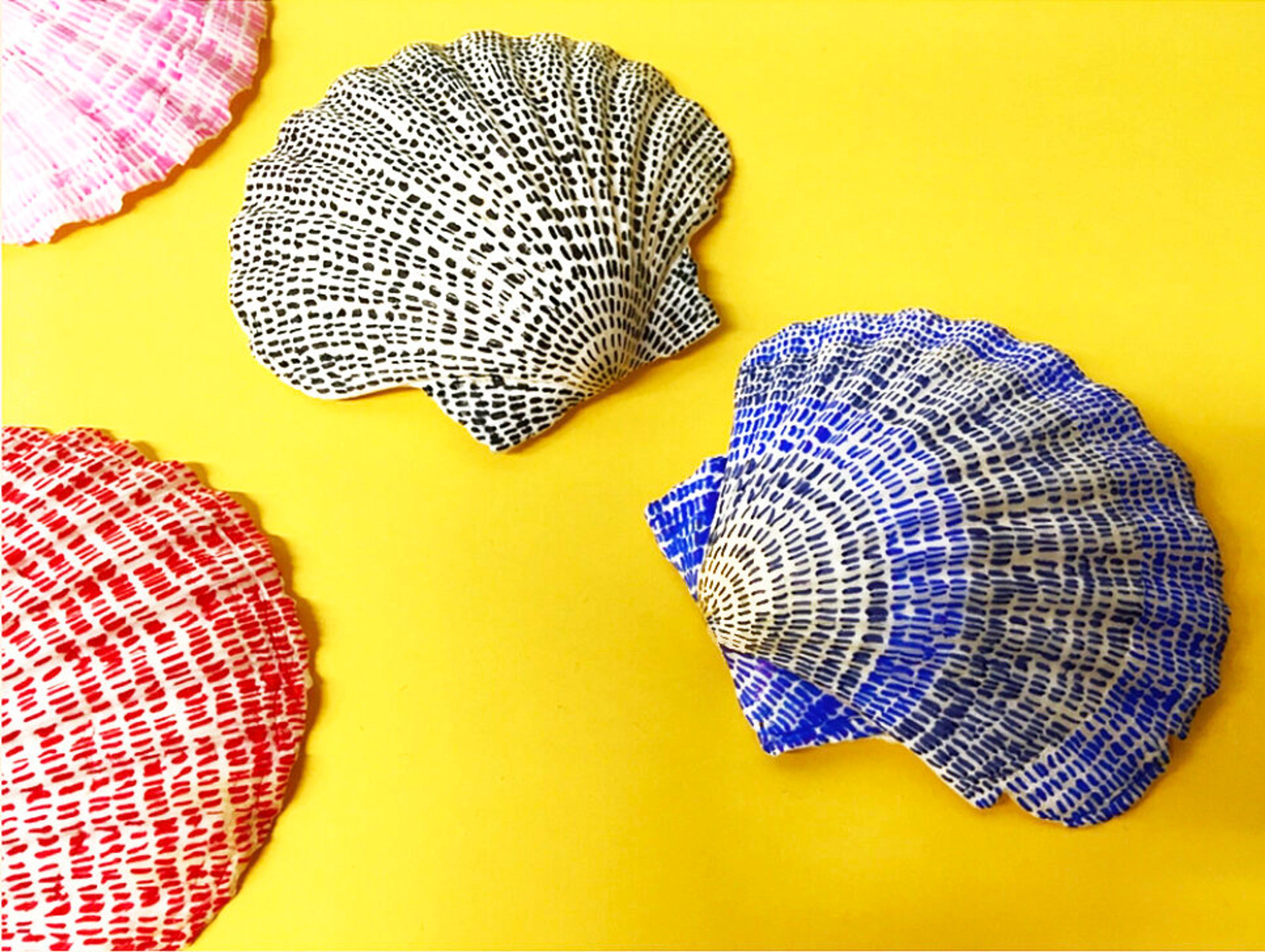 Four sea shells on a yellow background, each illustrated with a series of small line marks.
