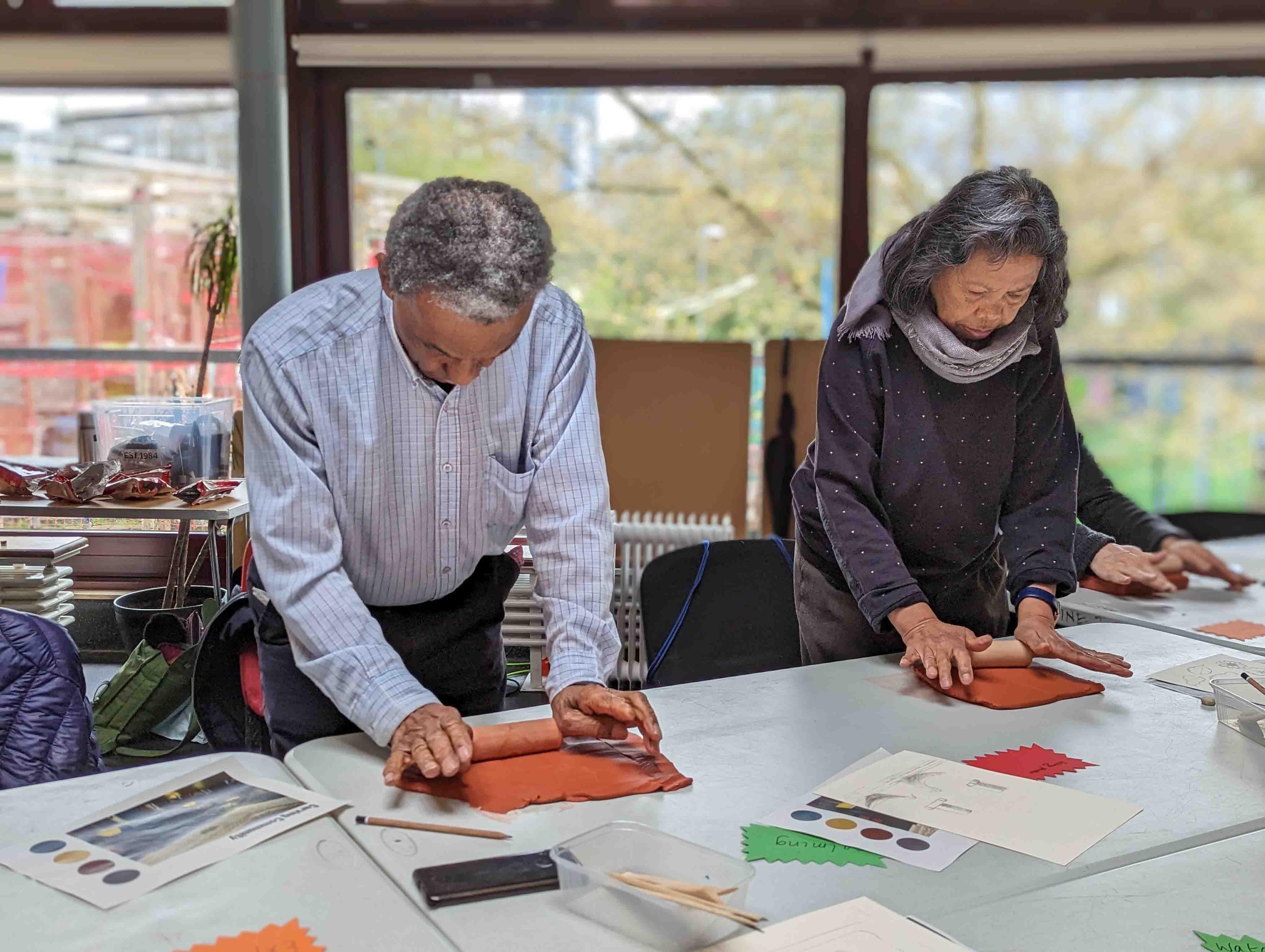 Two people working with clay on a table.