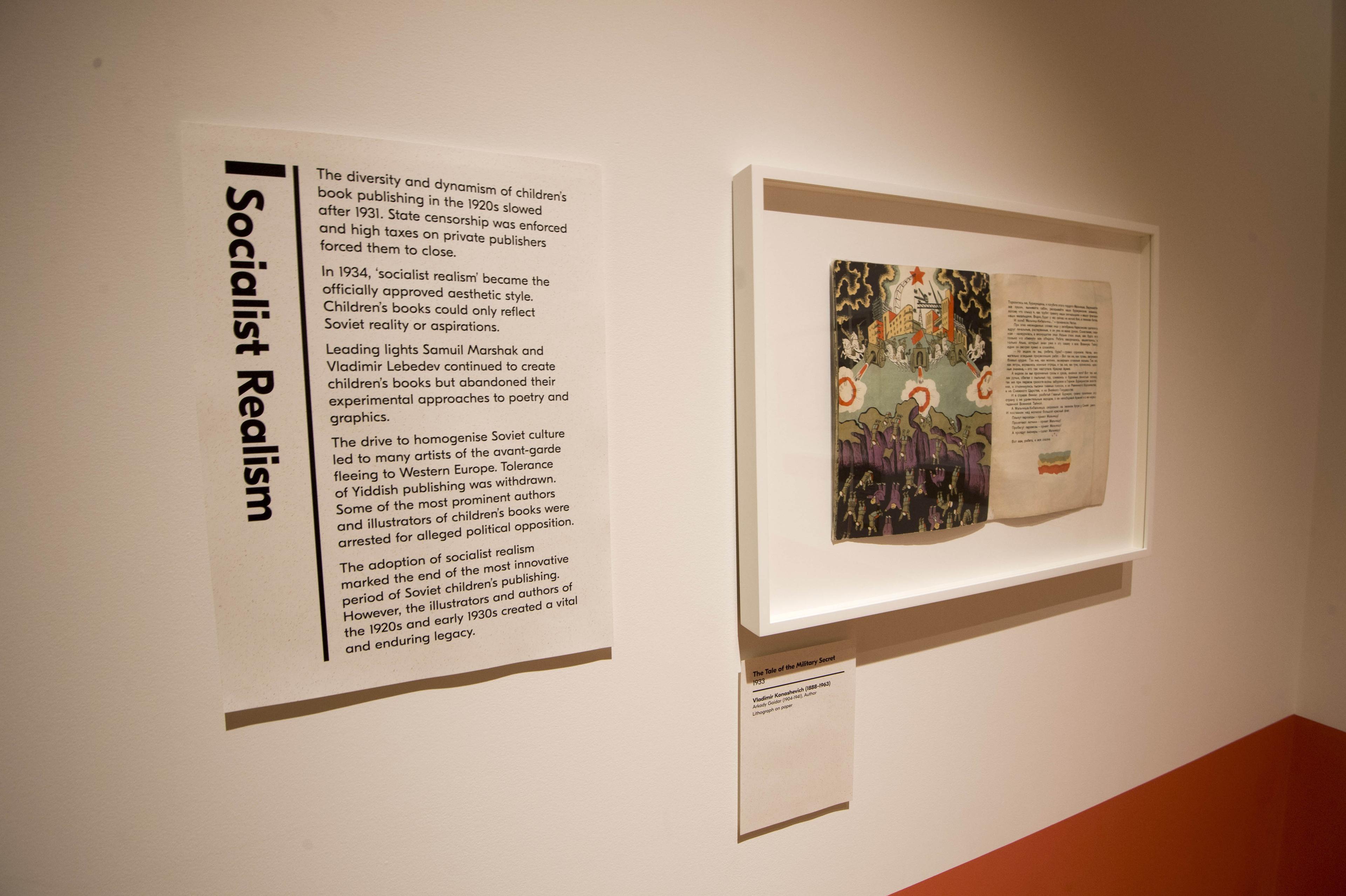 Inside an exhibition space with a text panel and framed illustration on the wall.