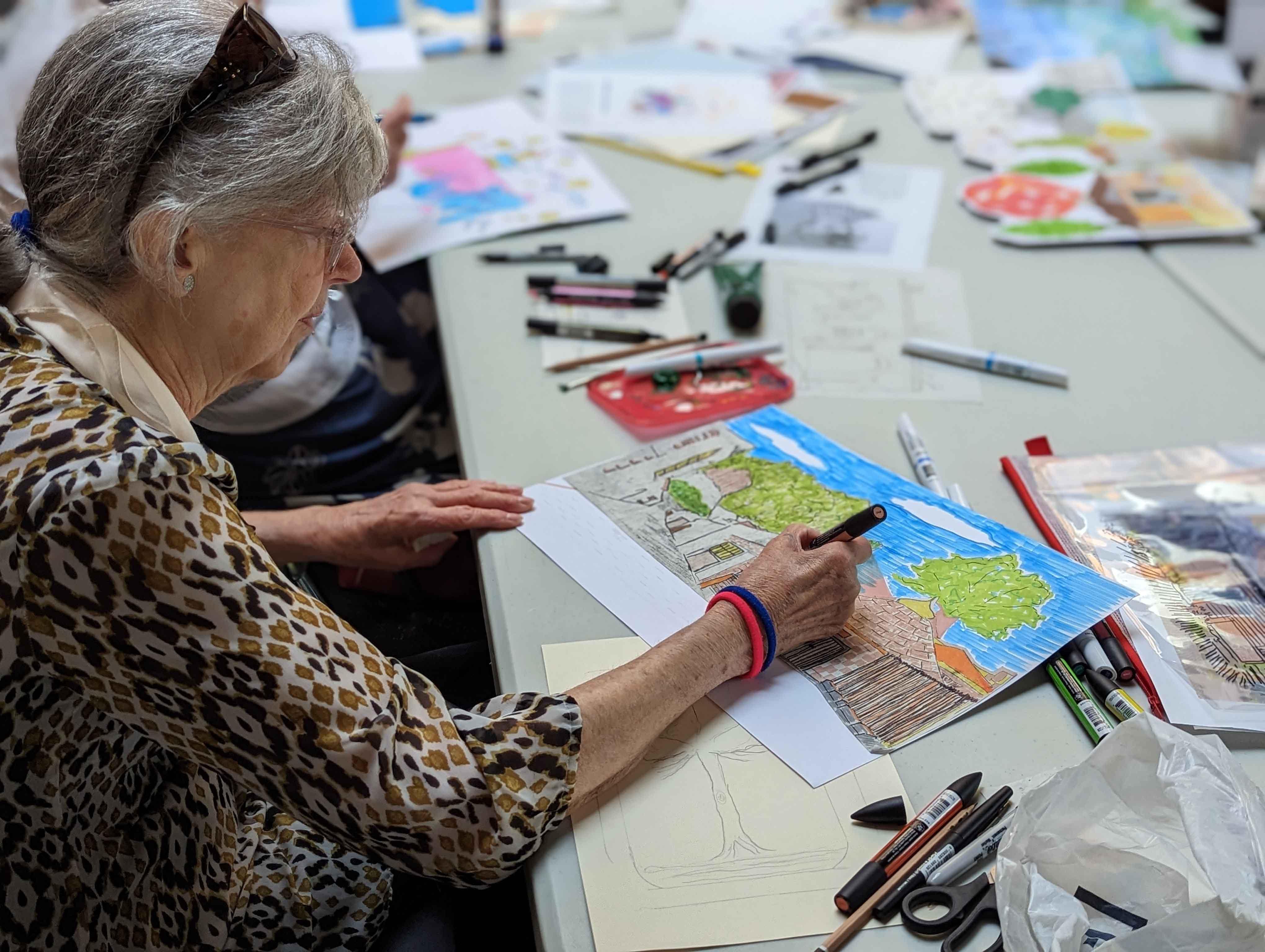 Person at a table illustrating a building on a piece of paper.
