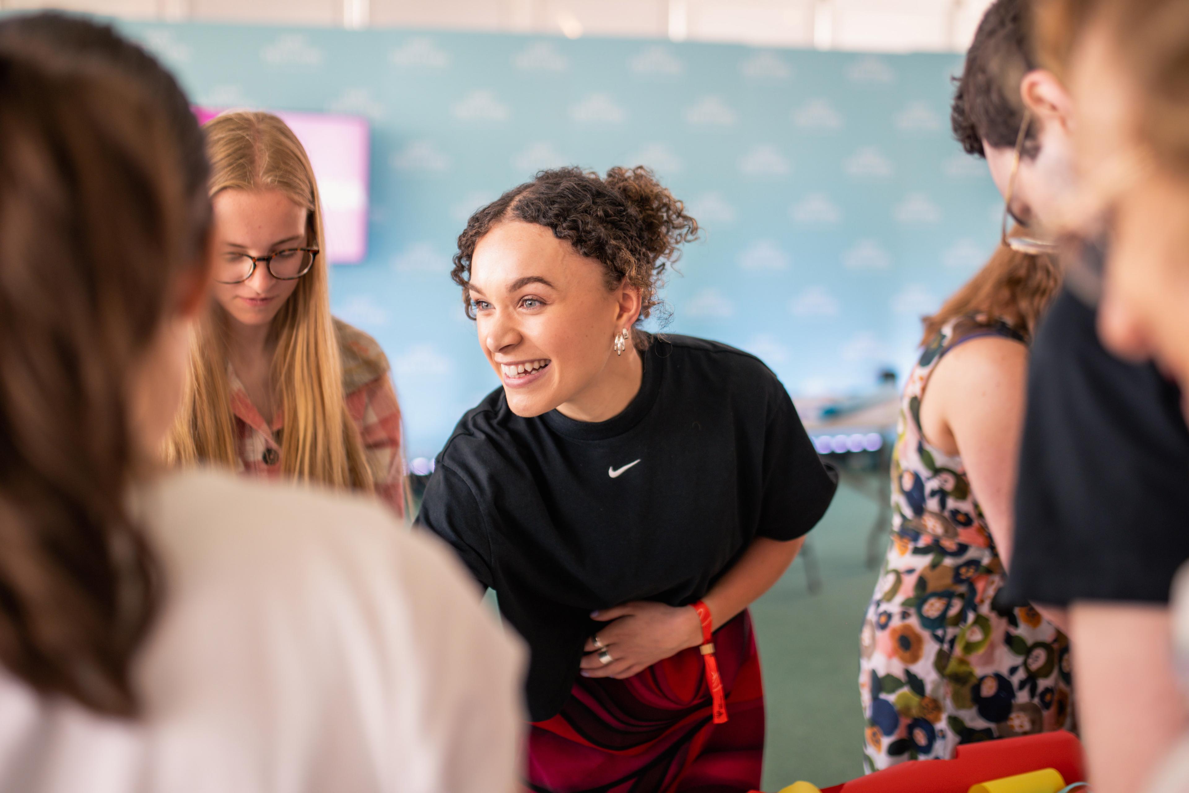 A smiling person is engaging with a group of people around them.