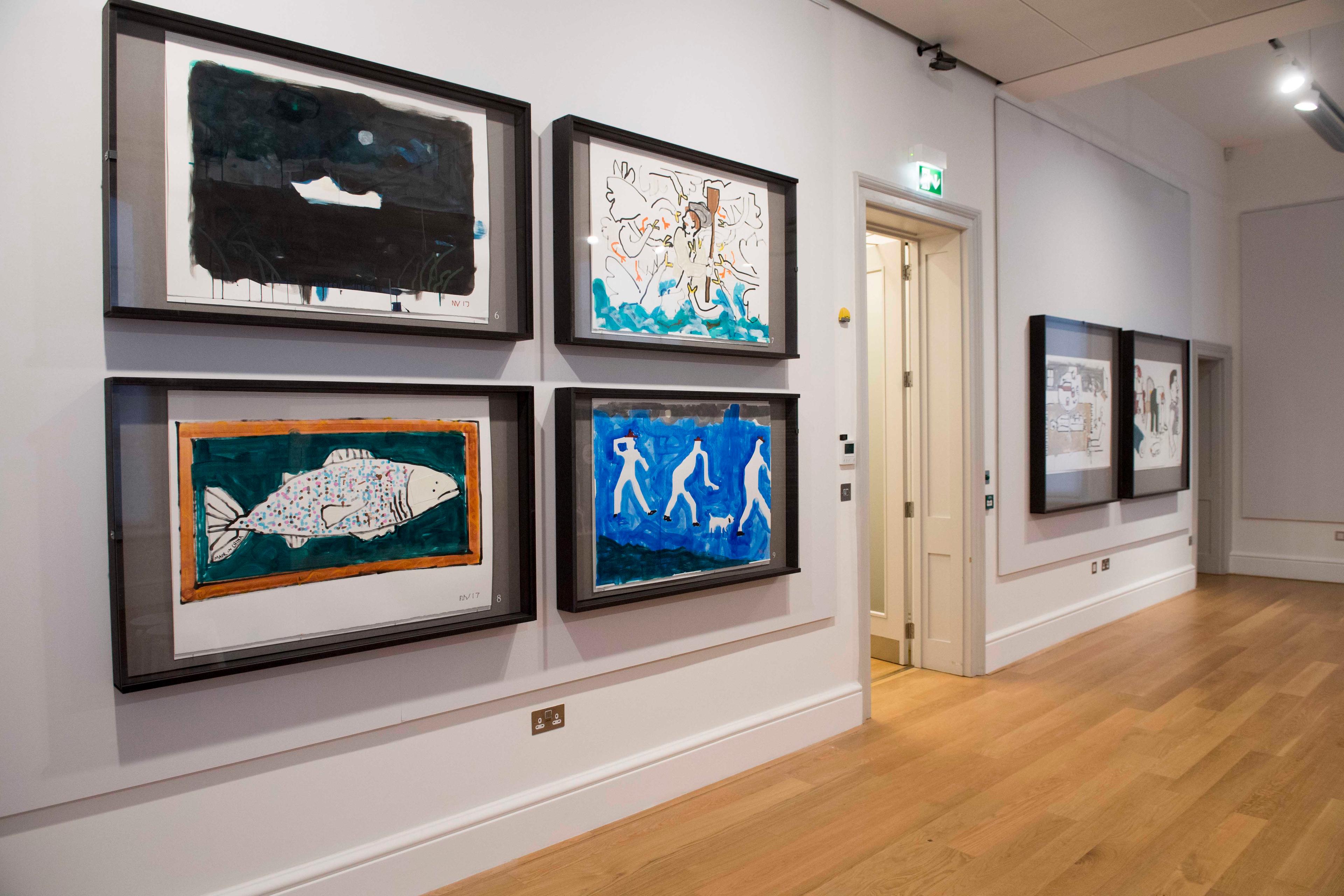 Large framed illustrations on display on the wall in an exhibition space.