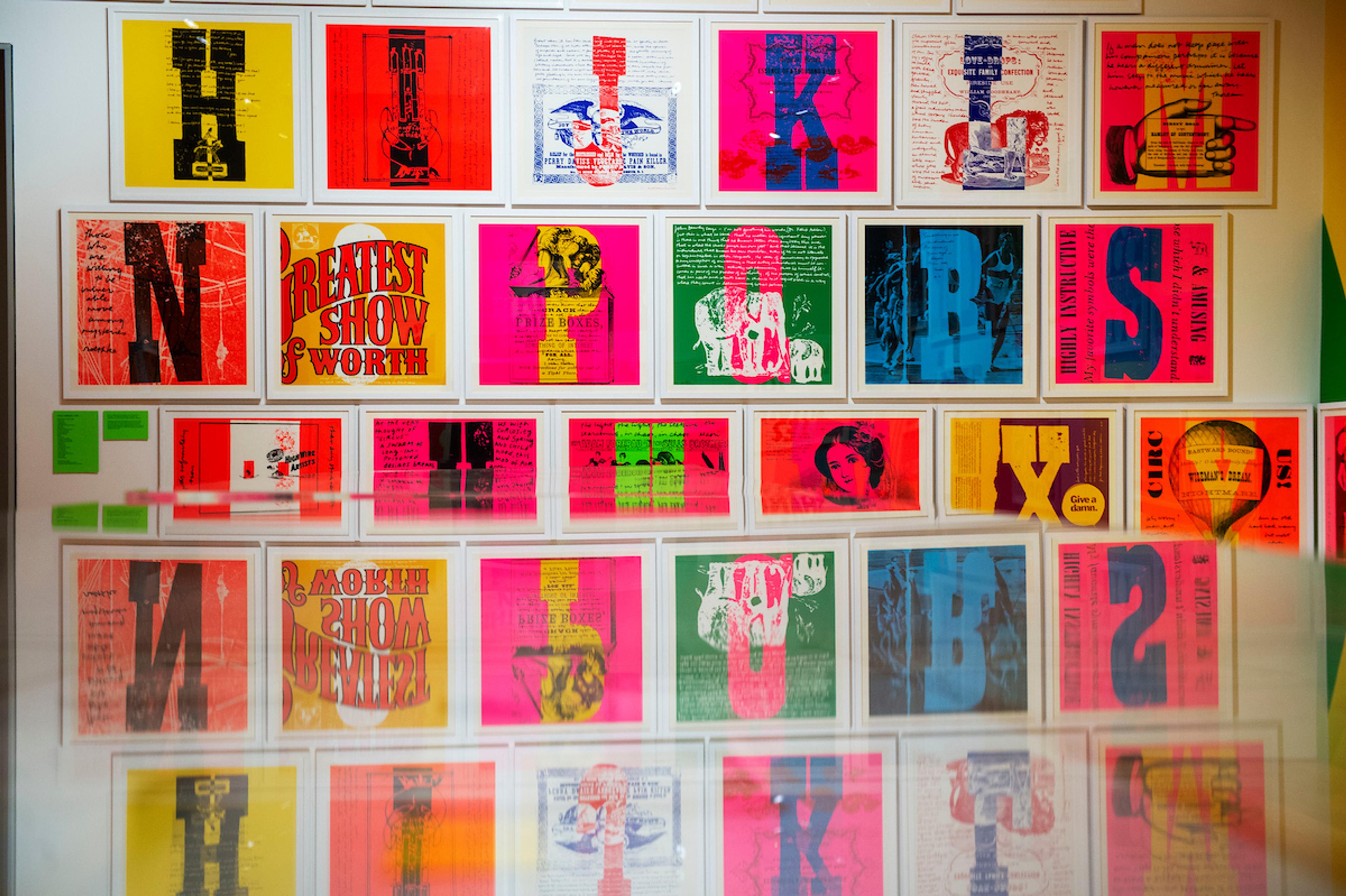 A wall of bright typography screen prints in white frames