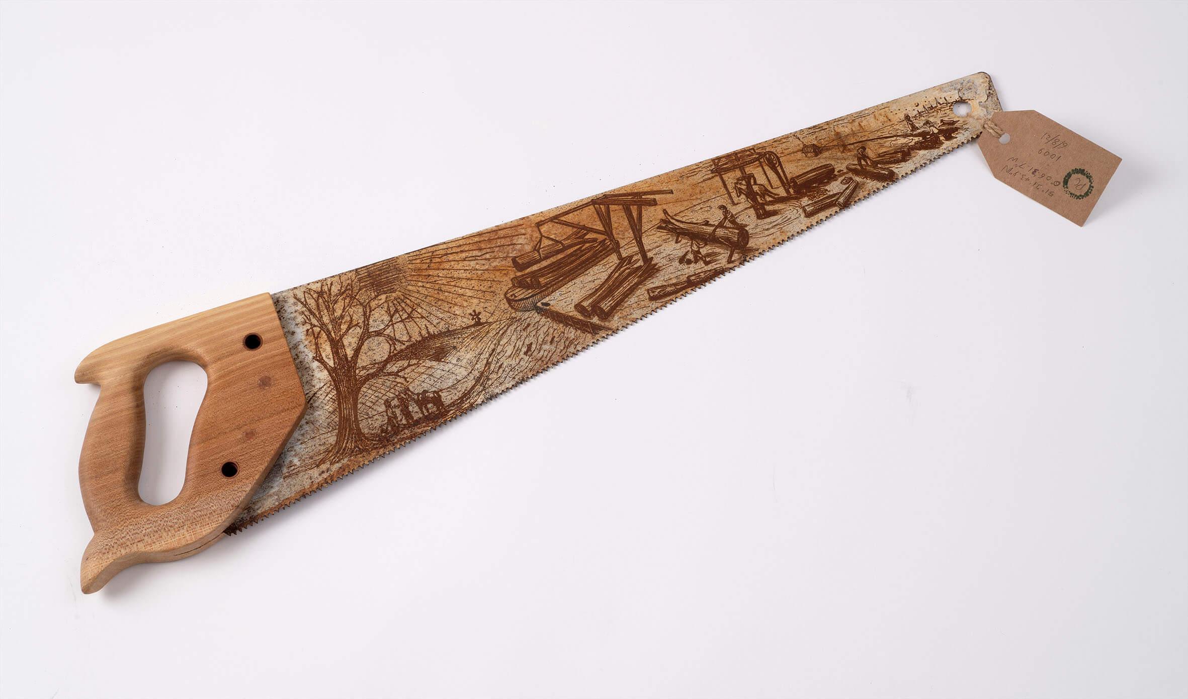 Photograph of a steel saw with etchings on it.