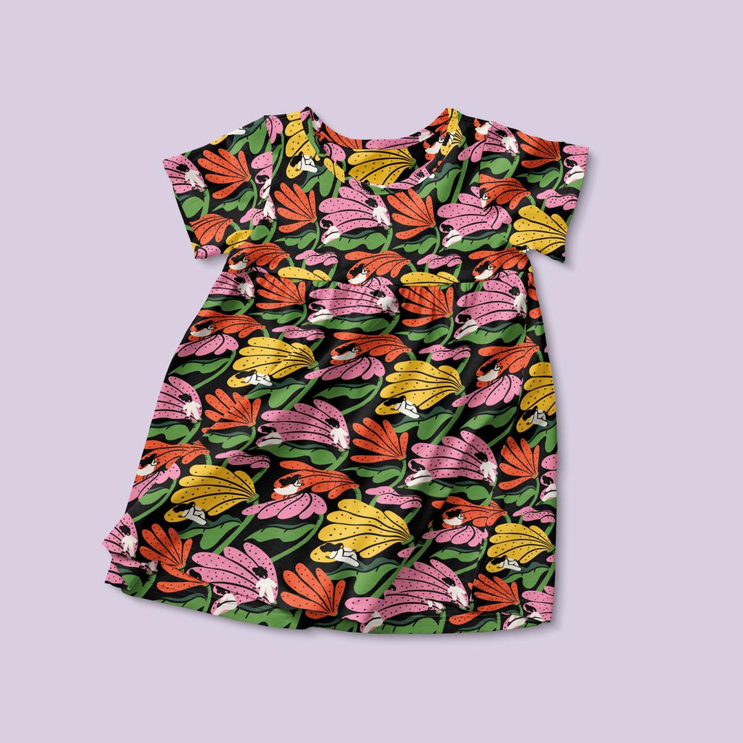 A child's dress with a repeat pattern with multi-coloured flowers with a figure sitting on petals.