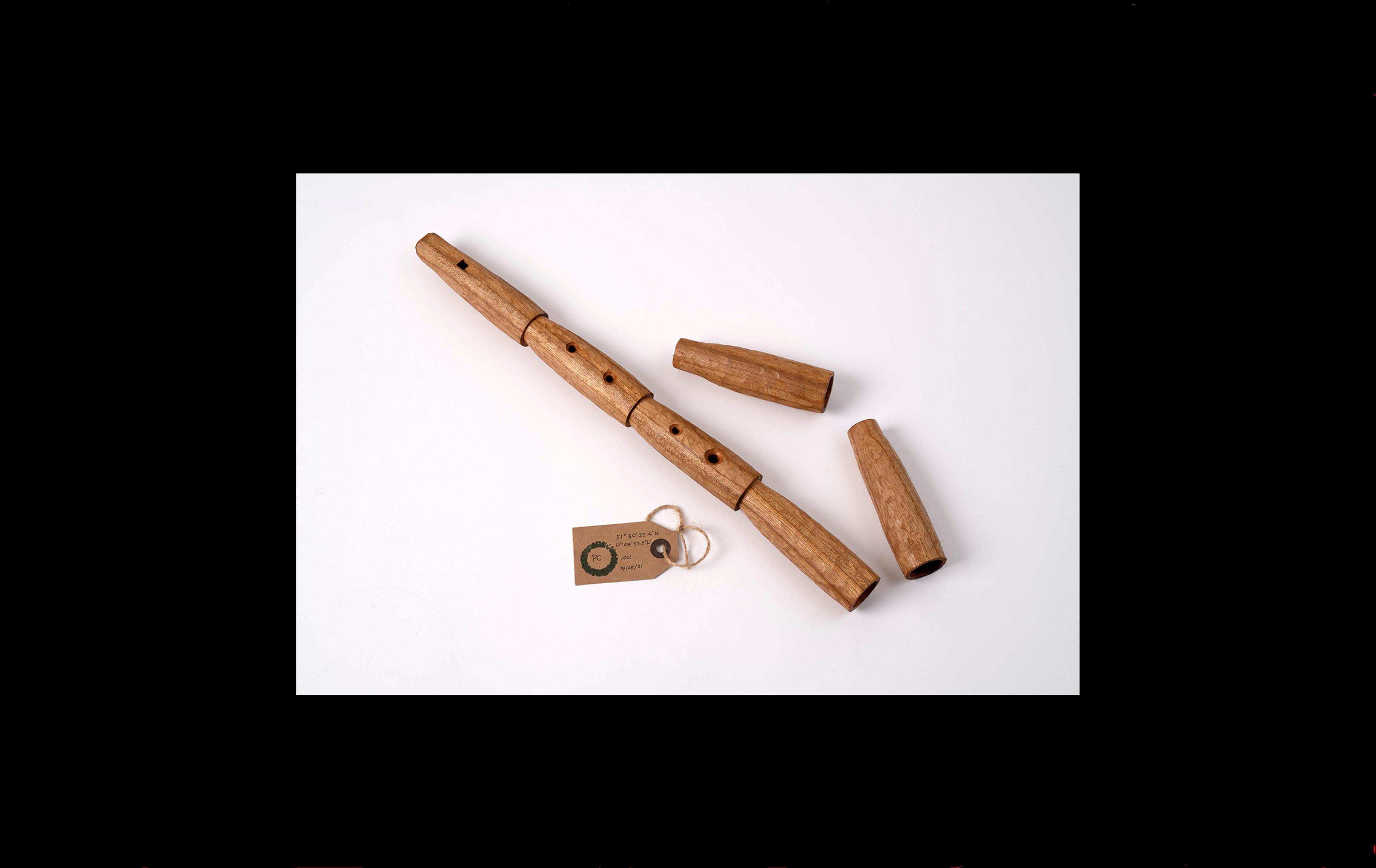 Photograph of a wooden musical pipe with finger holes, made of six sections with two sections separateds 