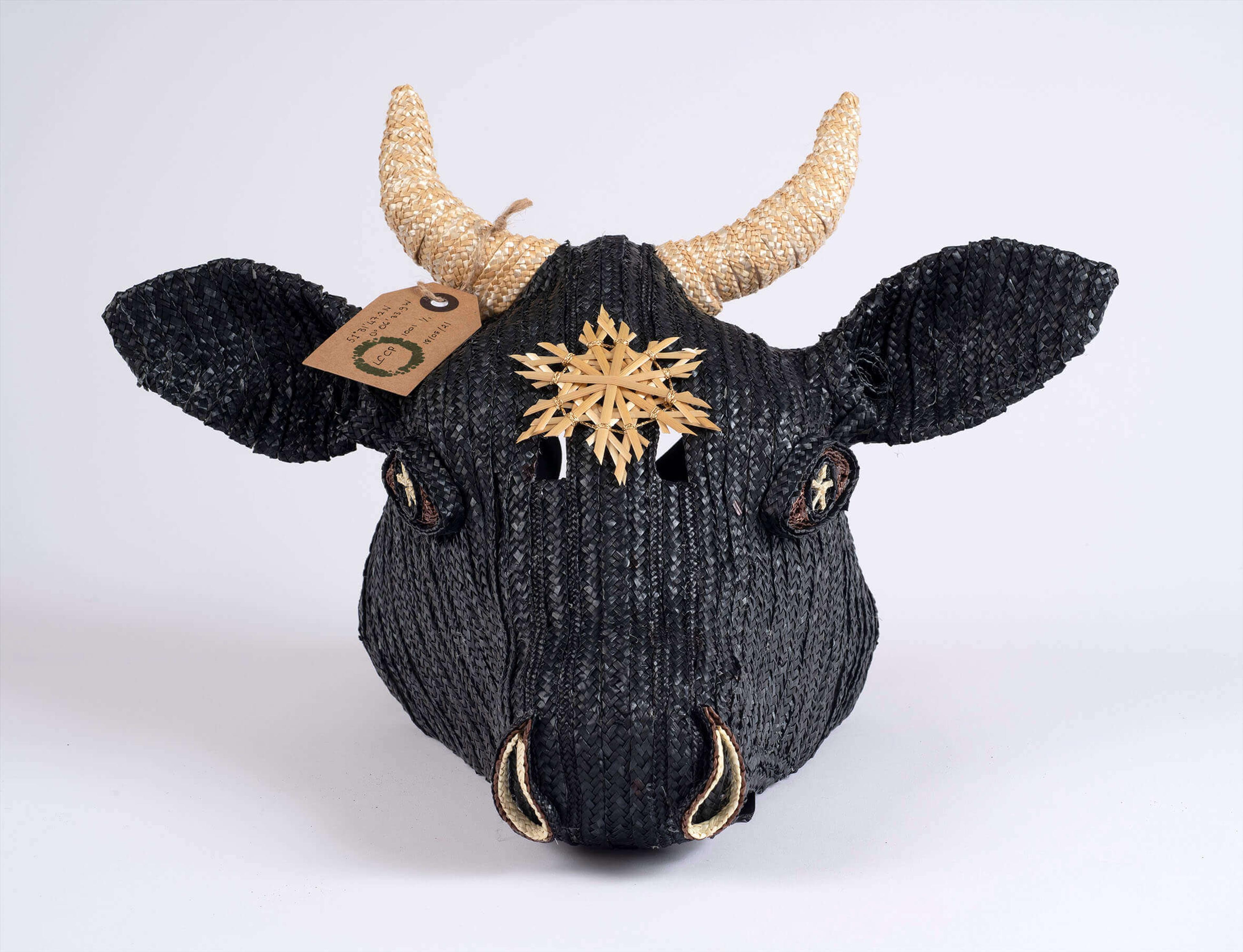 Black wicker cow's head with yellow wicker horns and straw star on the forehead
