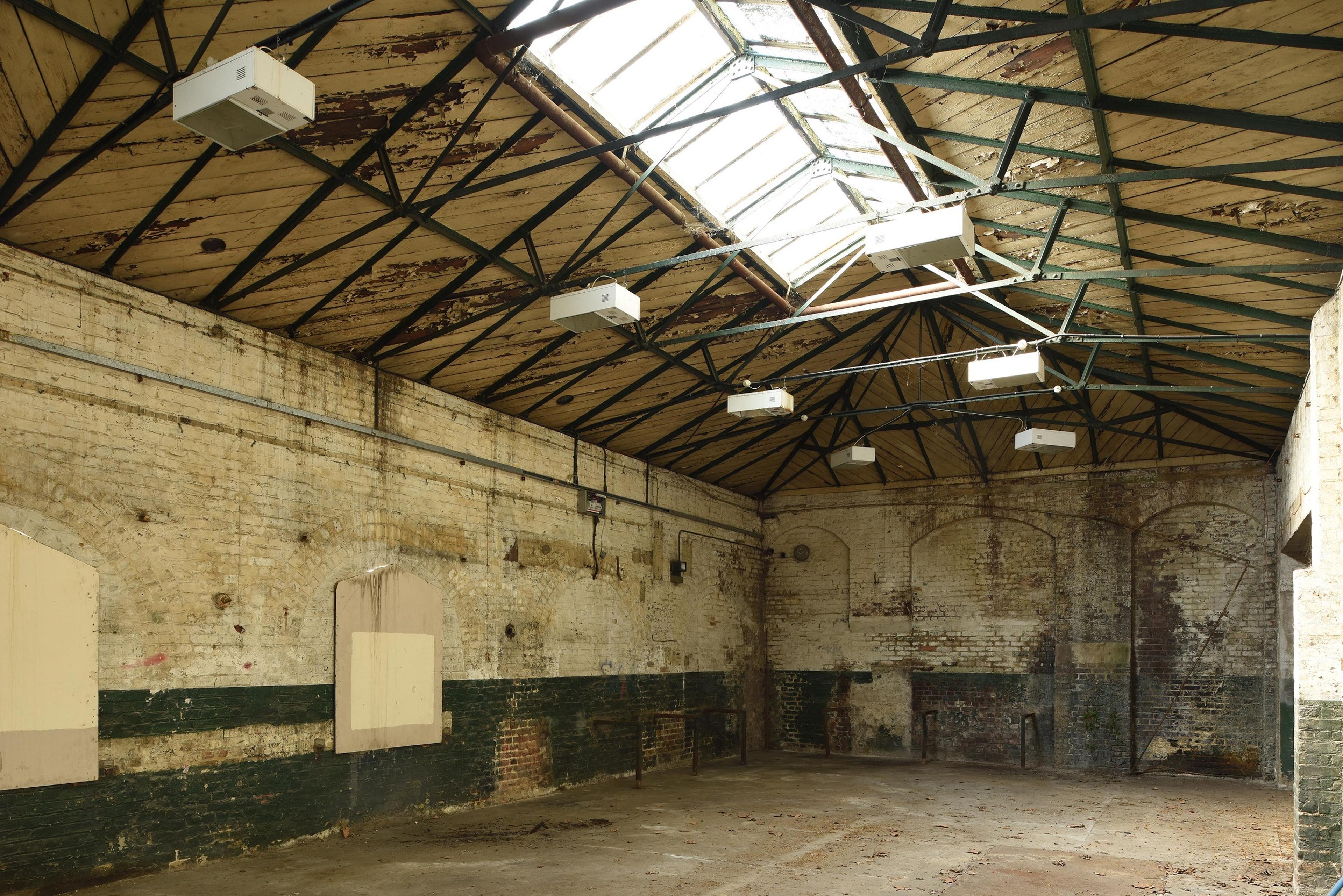 Interior of empty industrial brick building with exposed roof trusses and rooflight