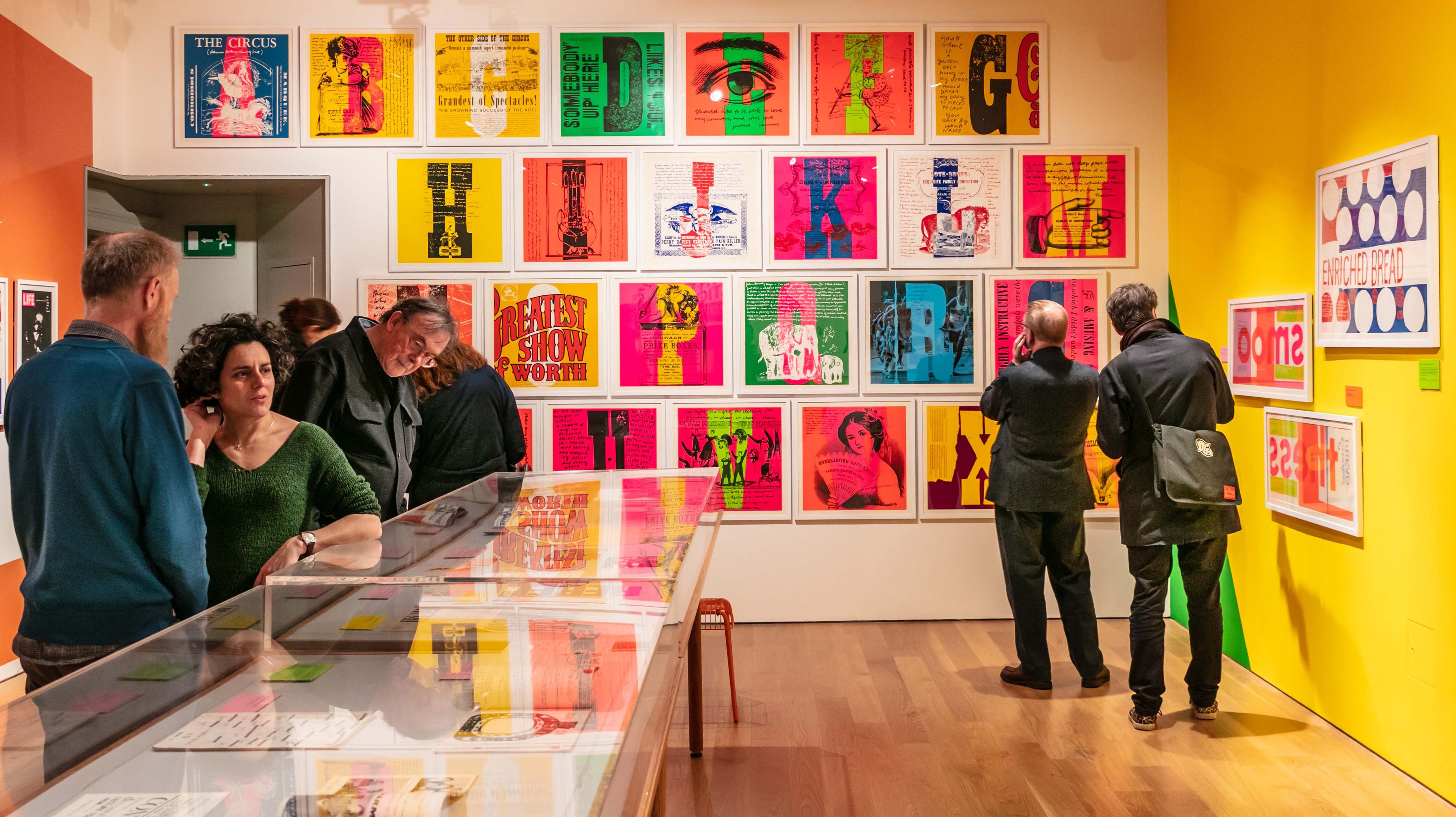 Photograph of the inside of a gallery with people looking at the illustrations on display