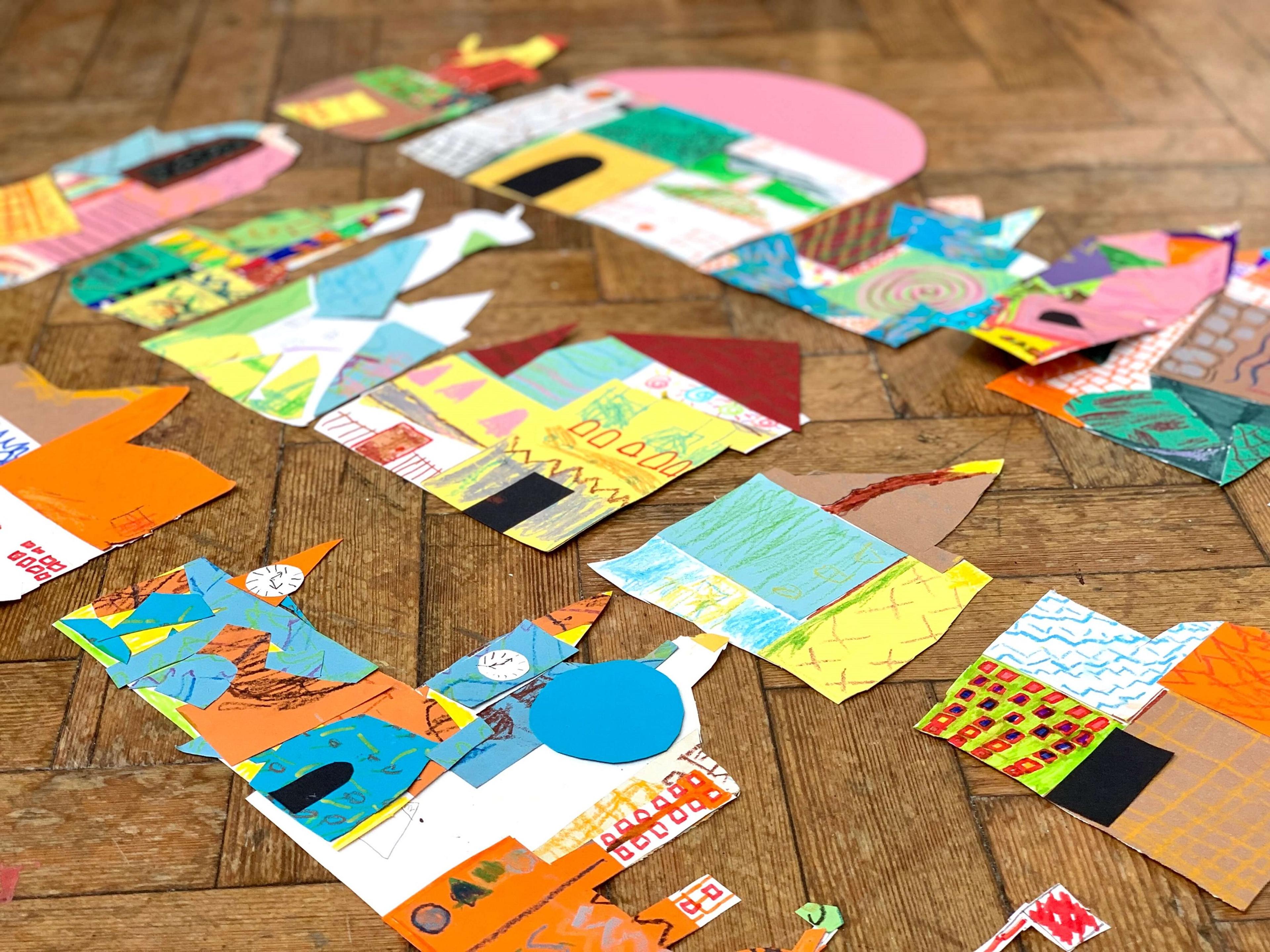 Brightly coloured collages of buildings laid out on a wooden floor