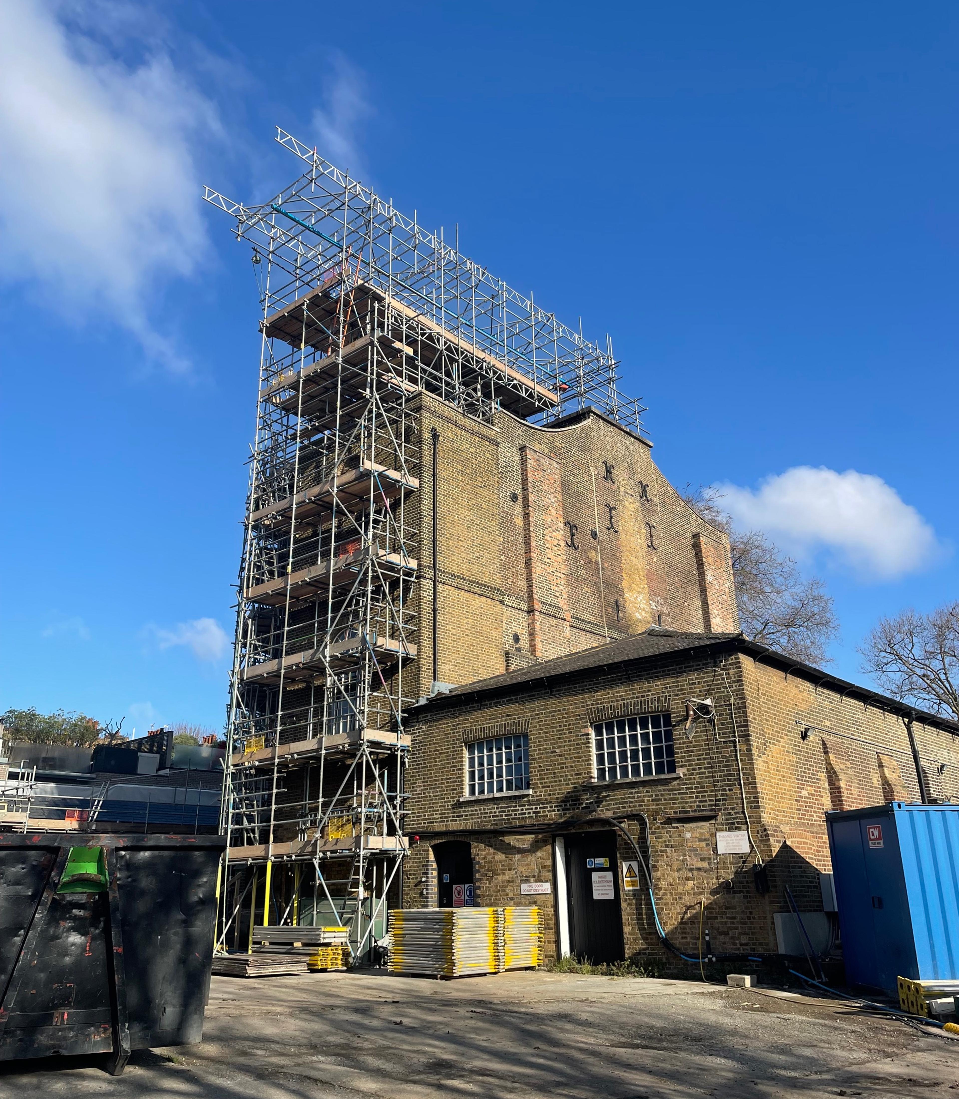 A photograph of a brick engine house with scaffolding on the outside