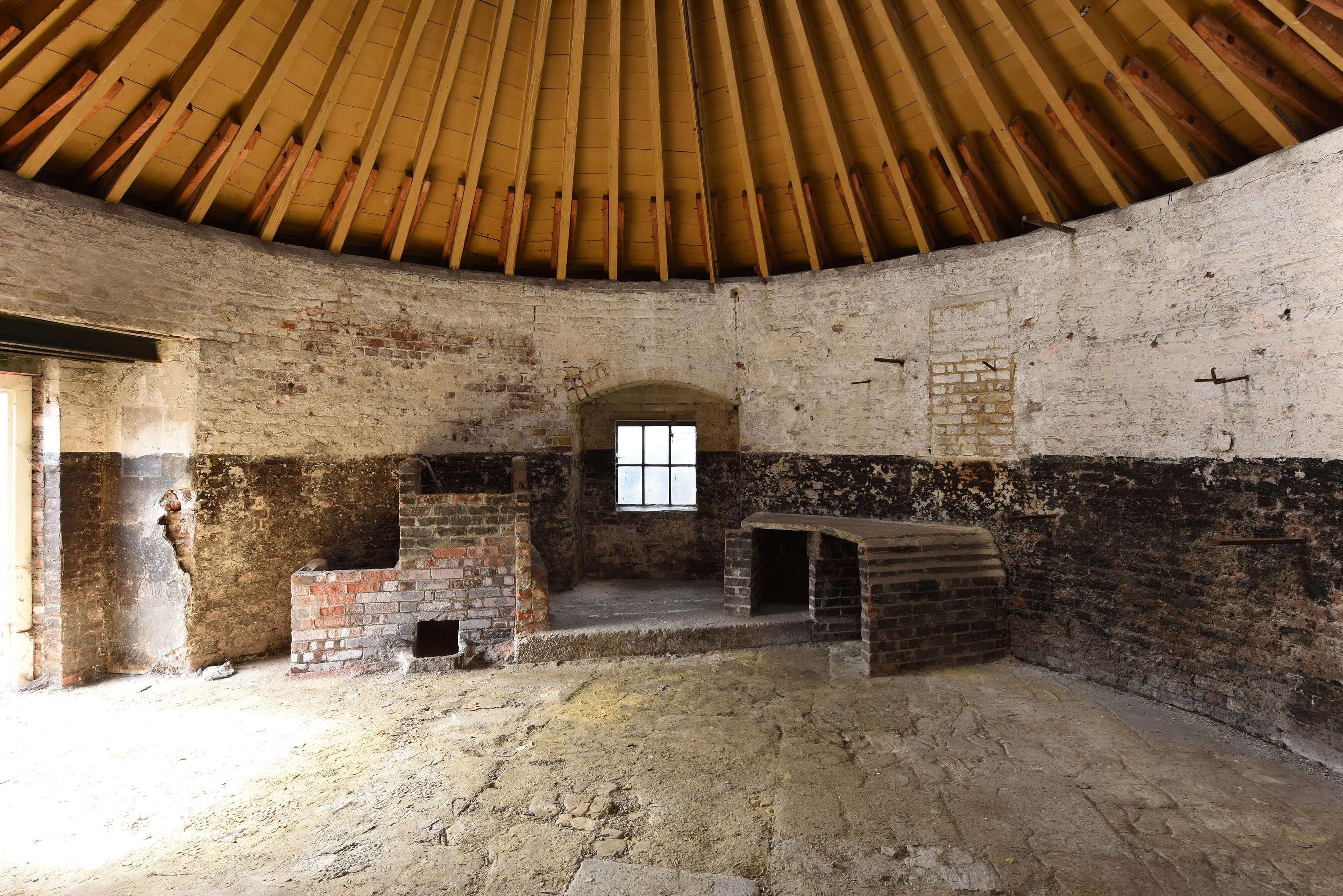 Inside a windmill base with brick walls and a wooden ceiling.
