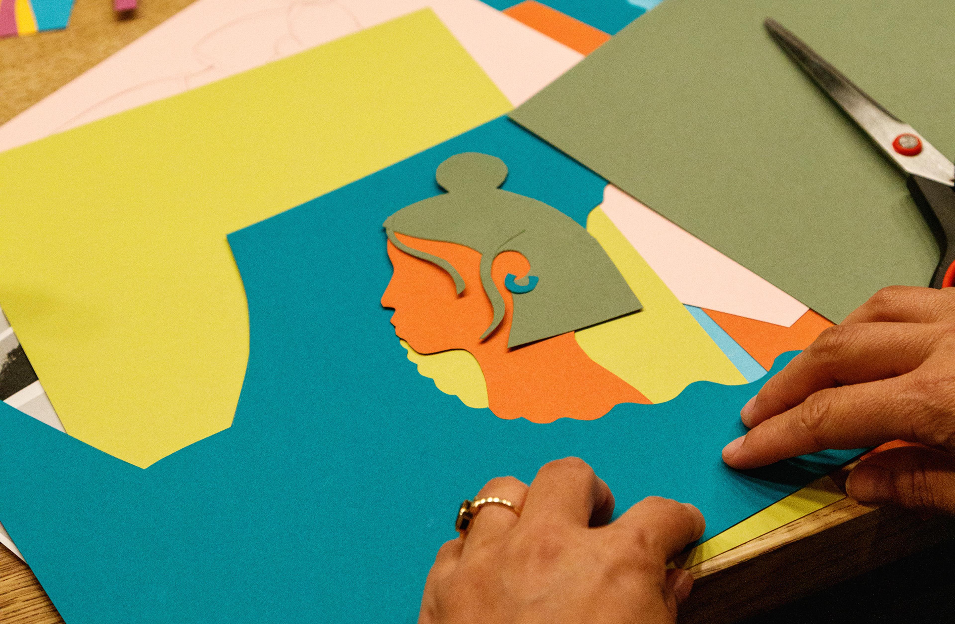 A pair of hands are making a collage of the side profile of a person using different coloured paper.