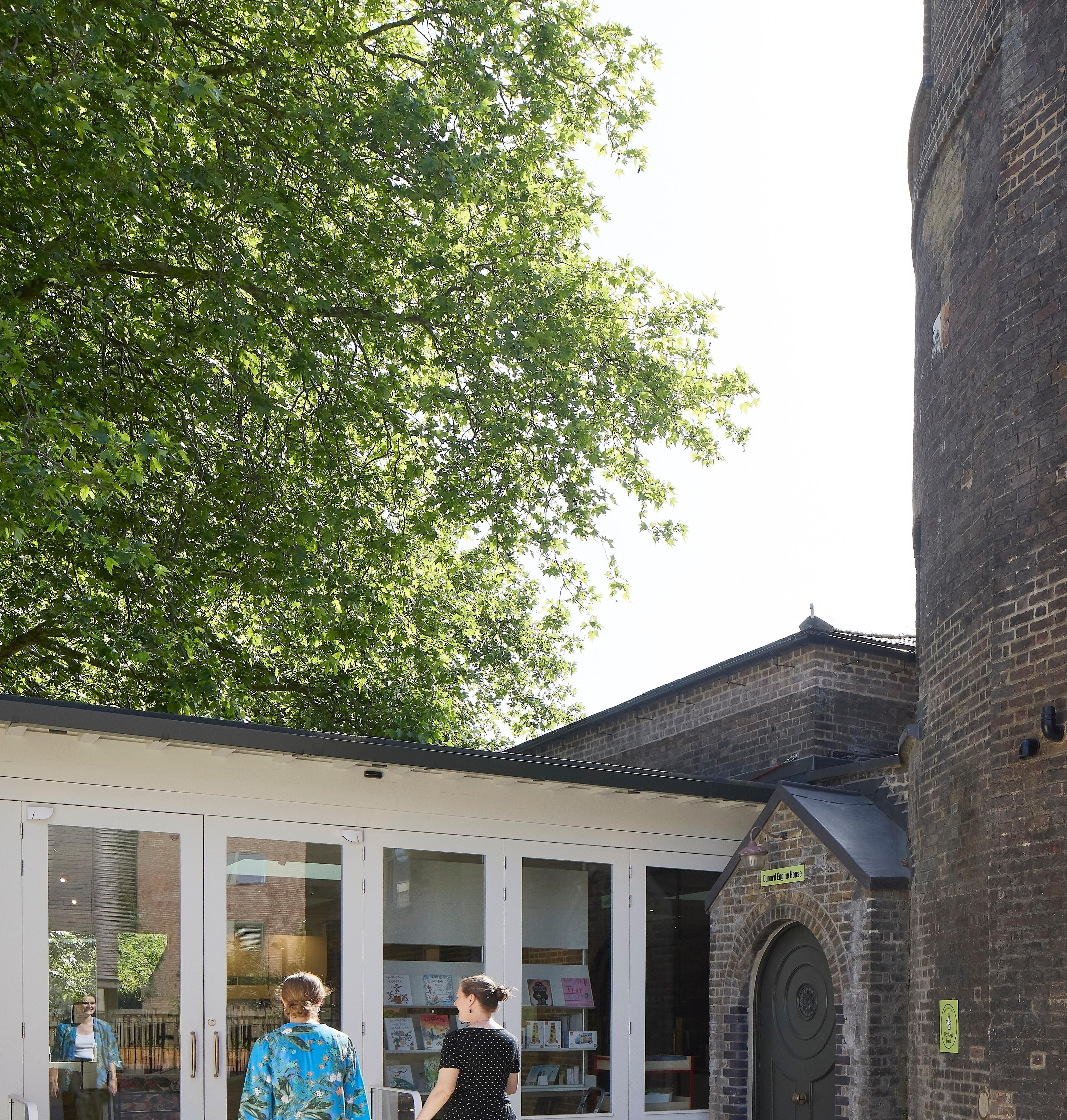 Two people walking toward the doors of a gallery space on a sunny day.