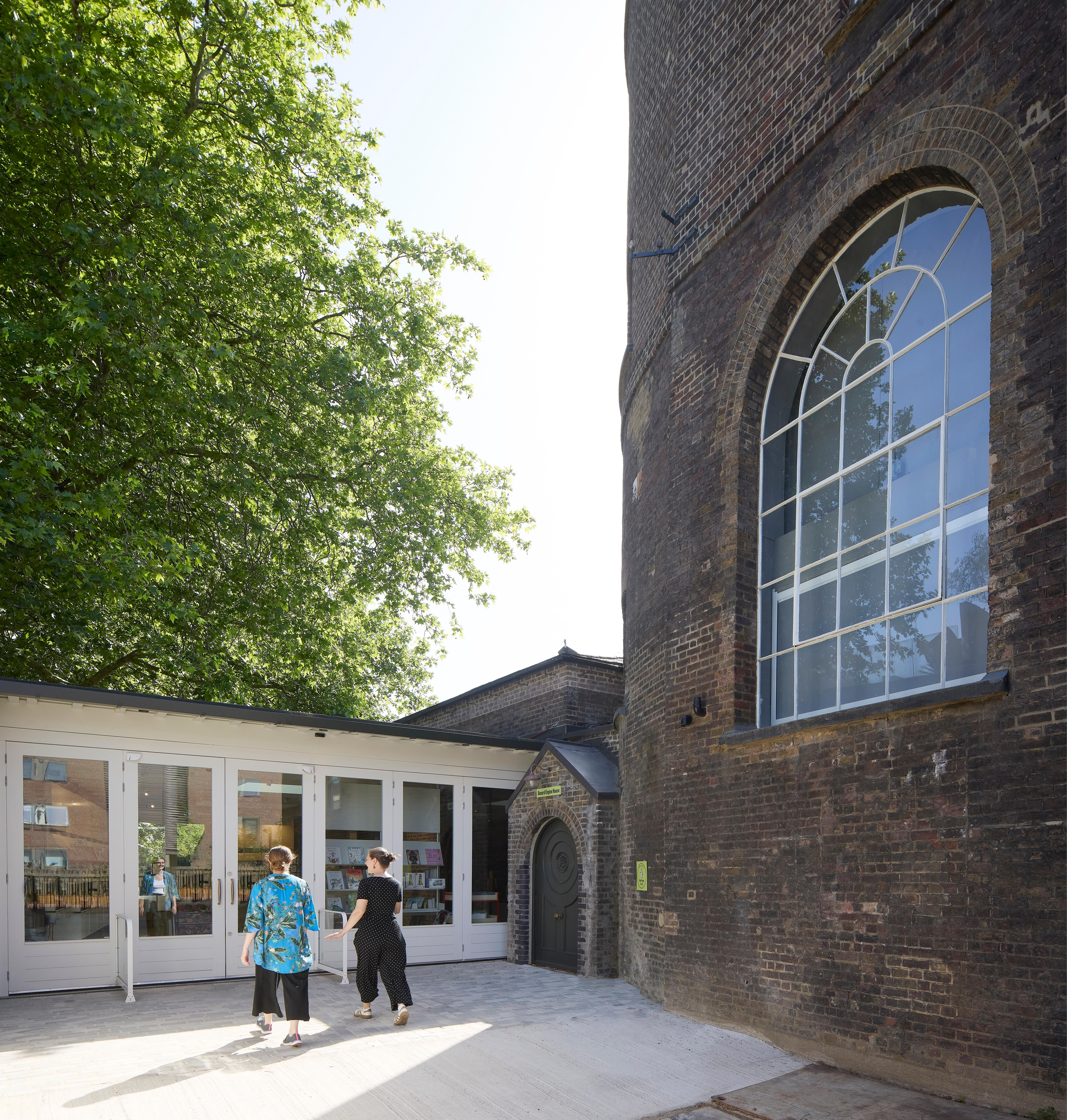 Two people walking toward the doors of a gallery space on a sunny day.