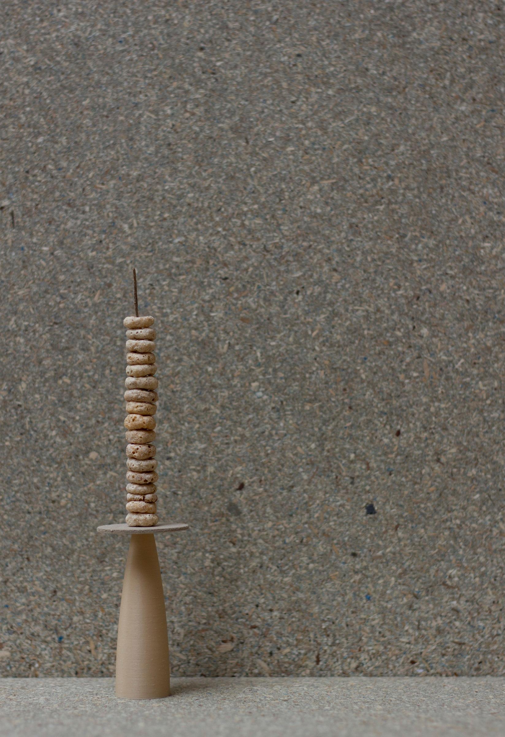 Photograph of a candle shape made from 3D objects, including a stack of Cheerios