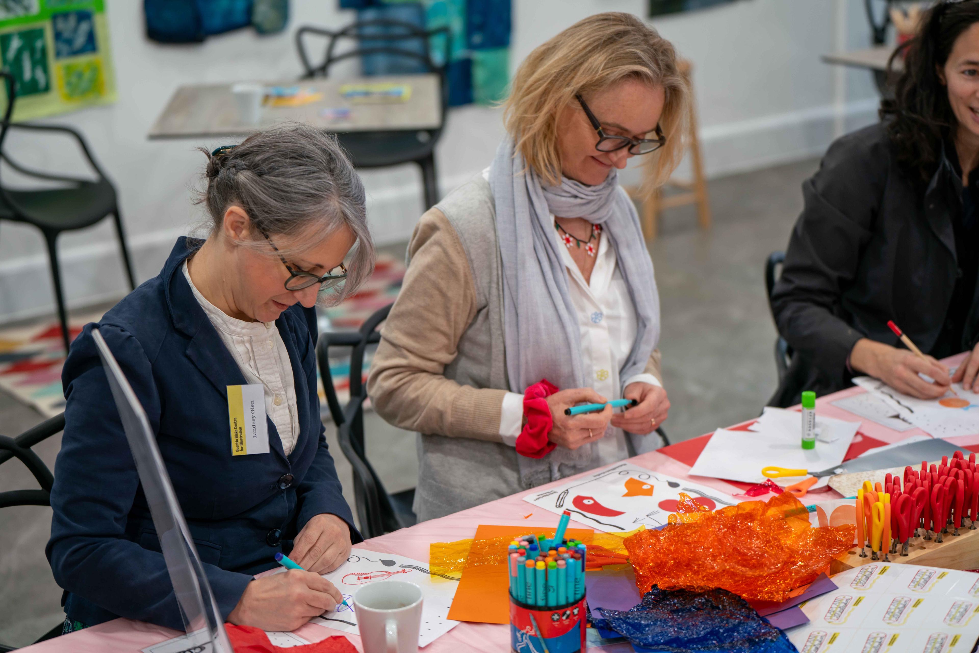 Photograph of three people at a table illustrating with pens and paper.