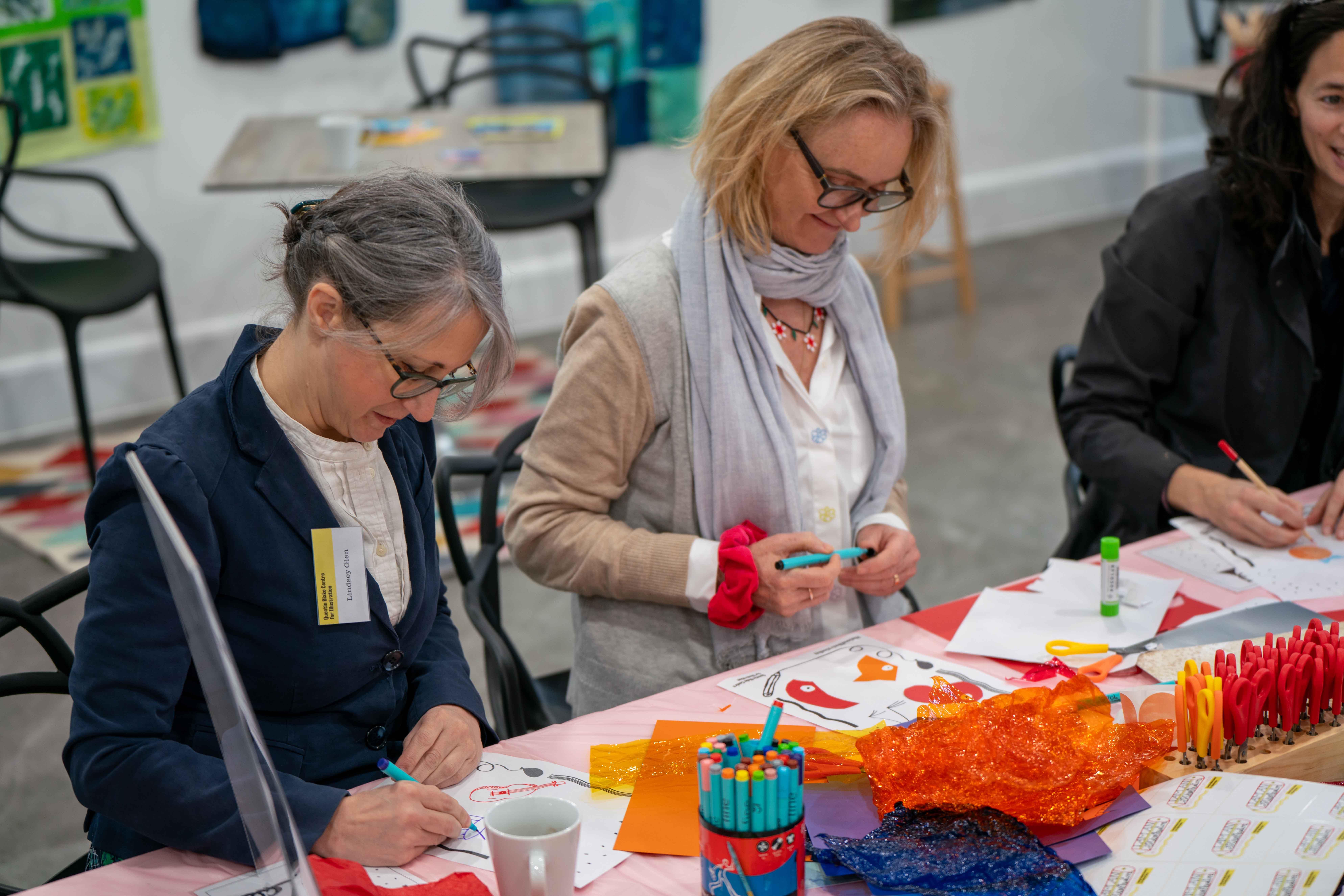 Photograph of three people at a table illustrating with pens and paper.