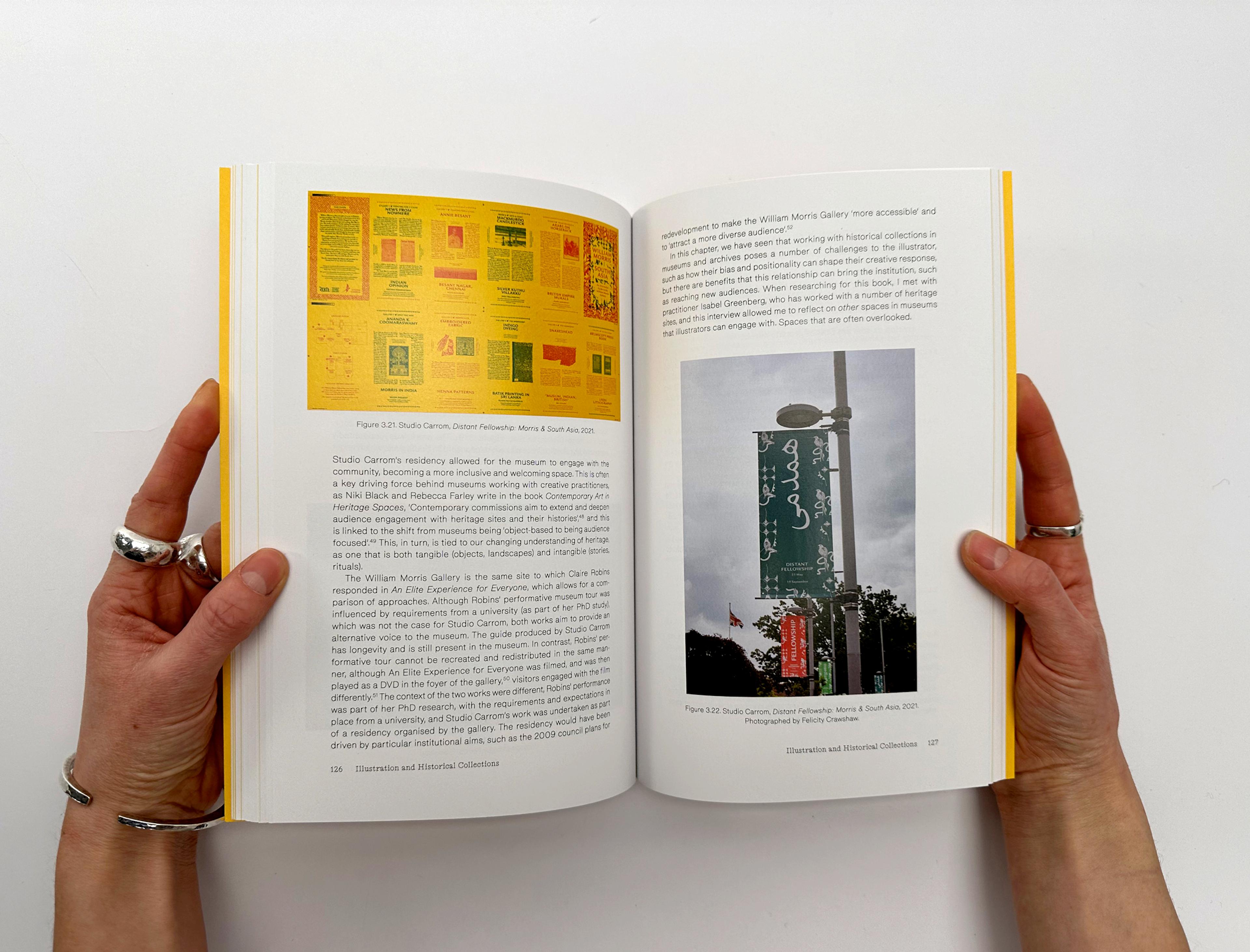 Photograph of two hands opening up a copy of the Illustration and Heritage book.