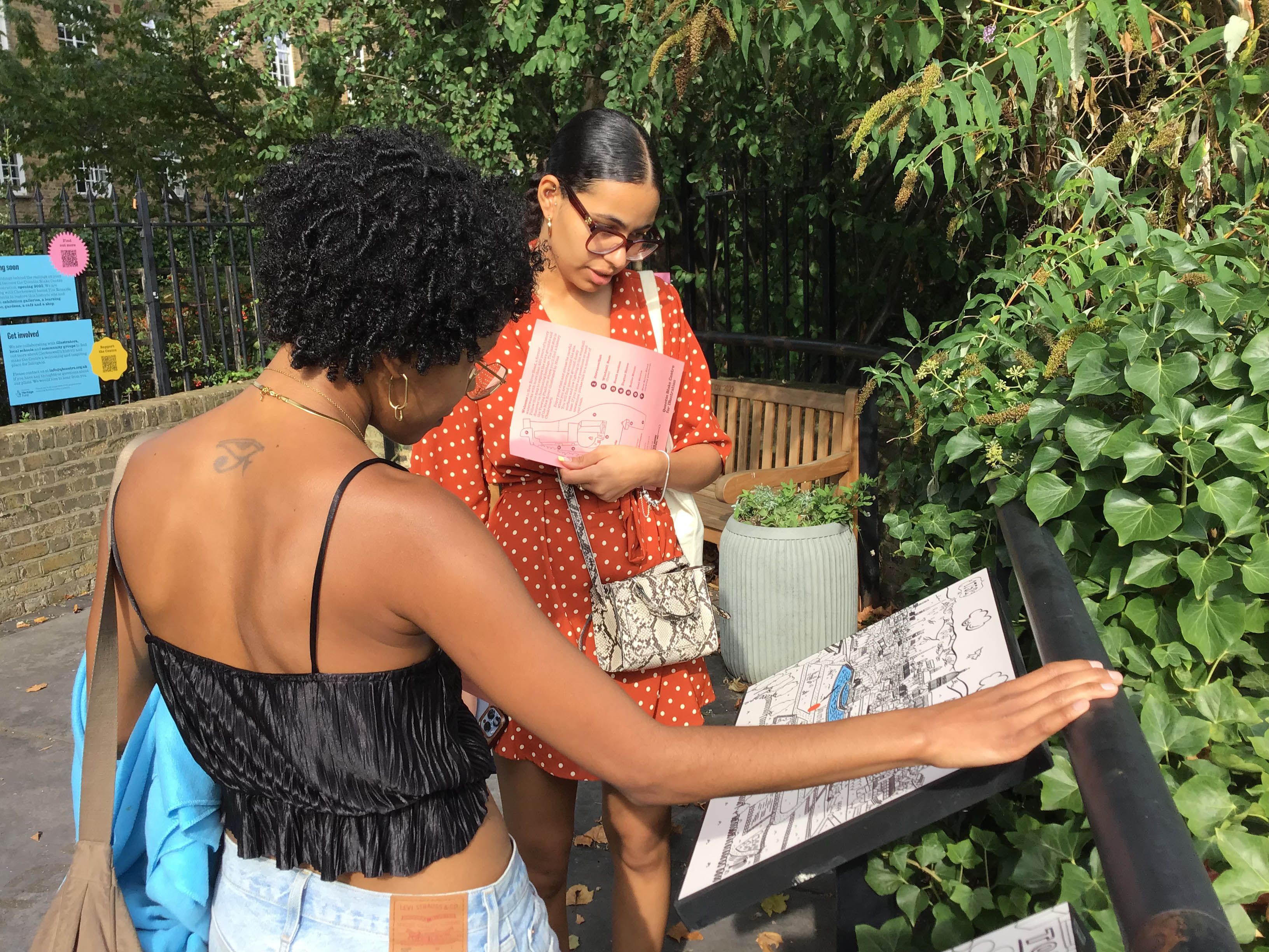 Two people reading a text panel outside