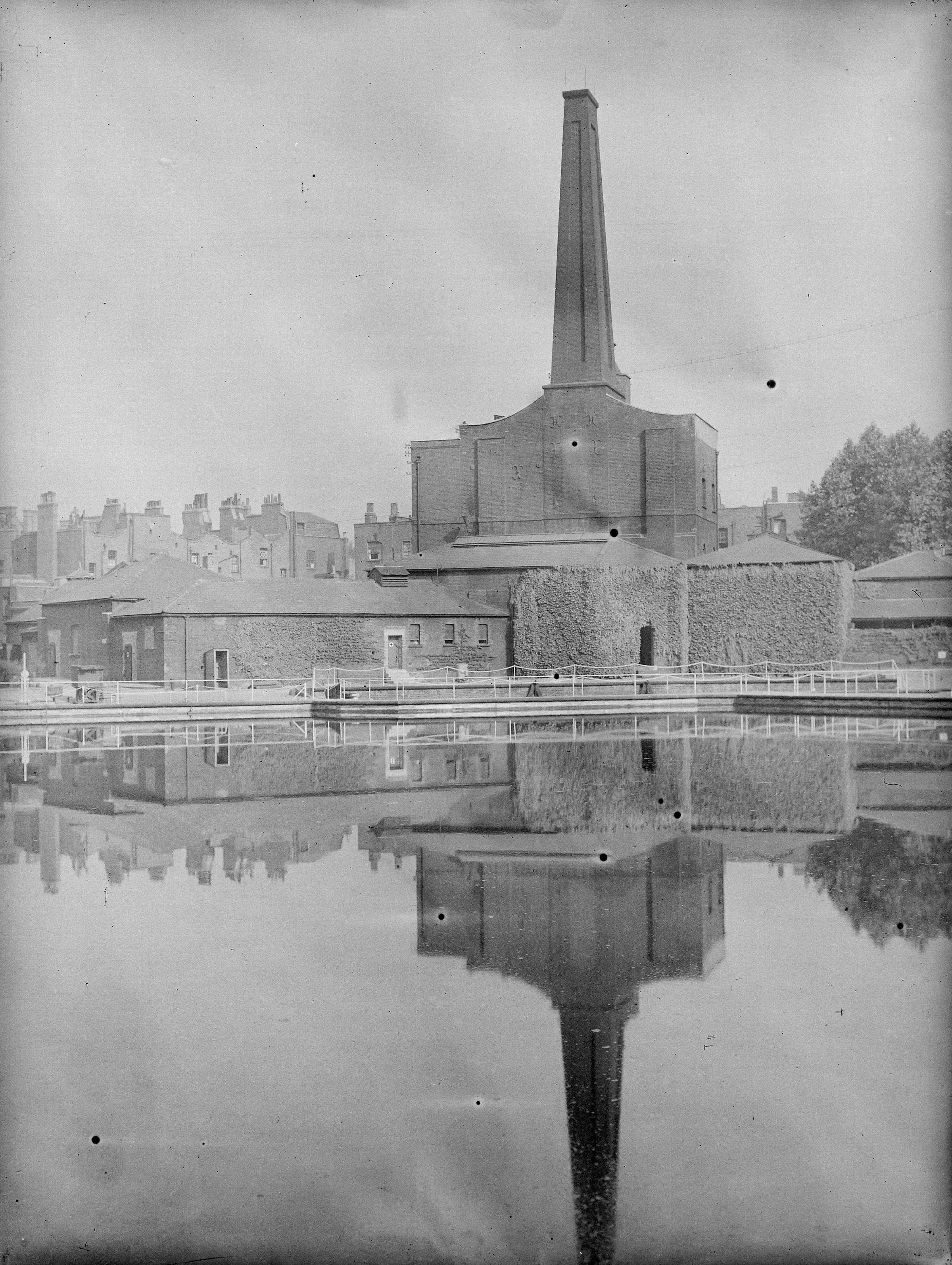 Industrial brick building with large building reflected in a pond in the foreground