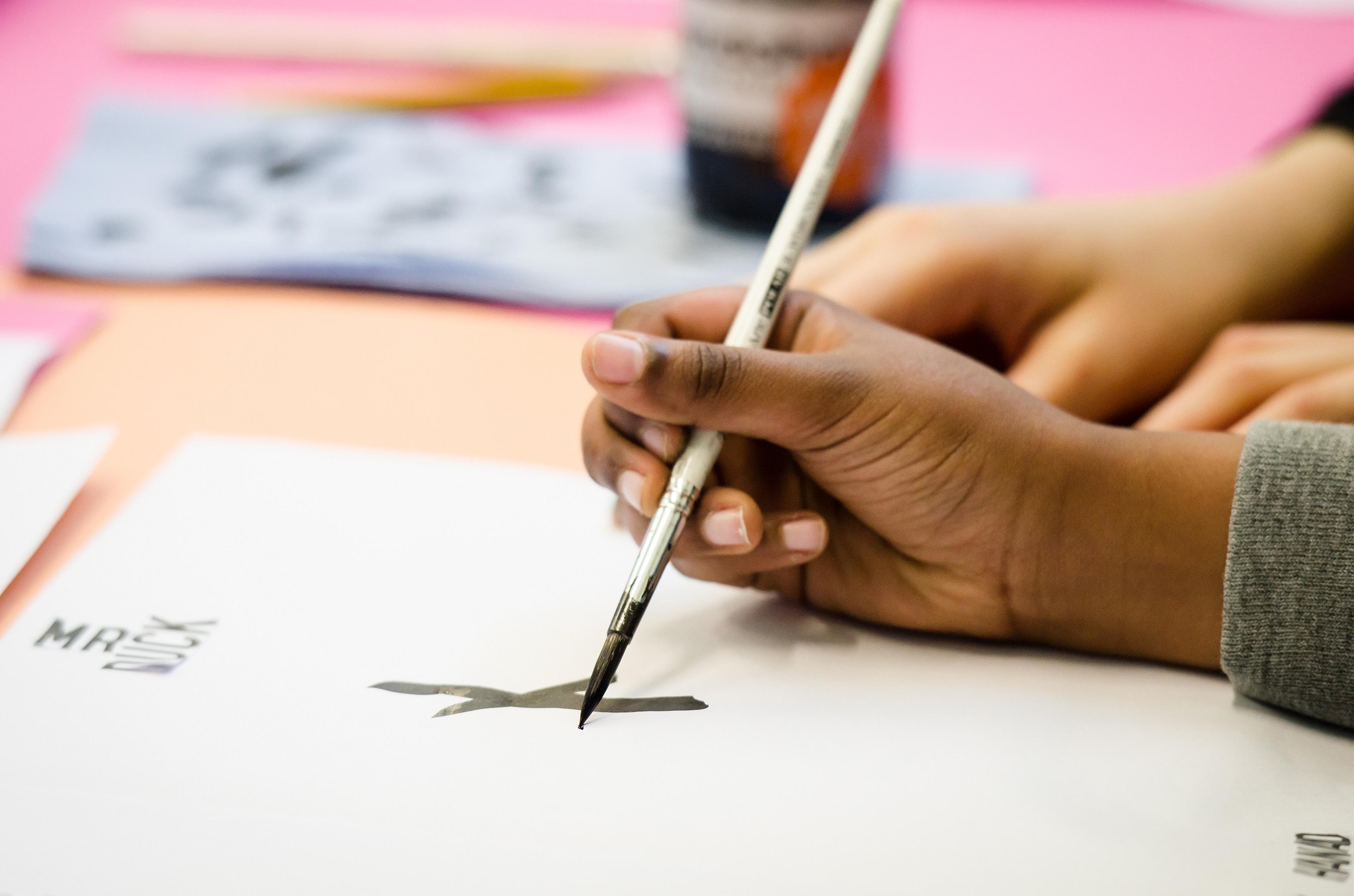 Photograph of a child's hand drawing with stick and ink