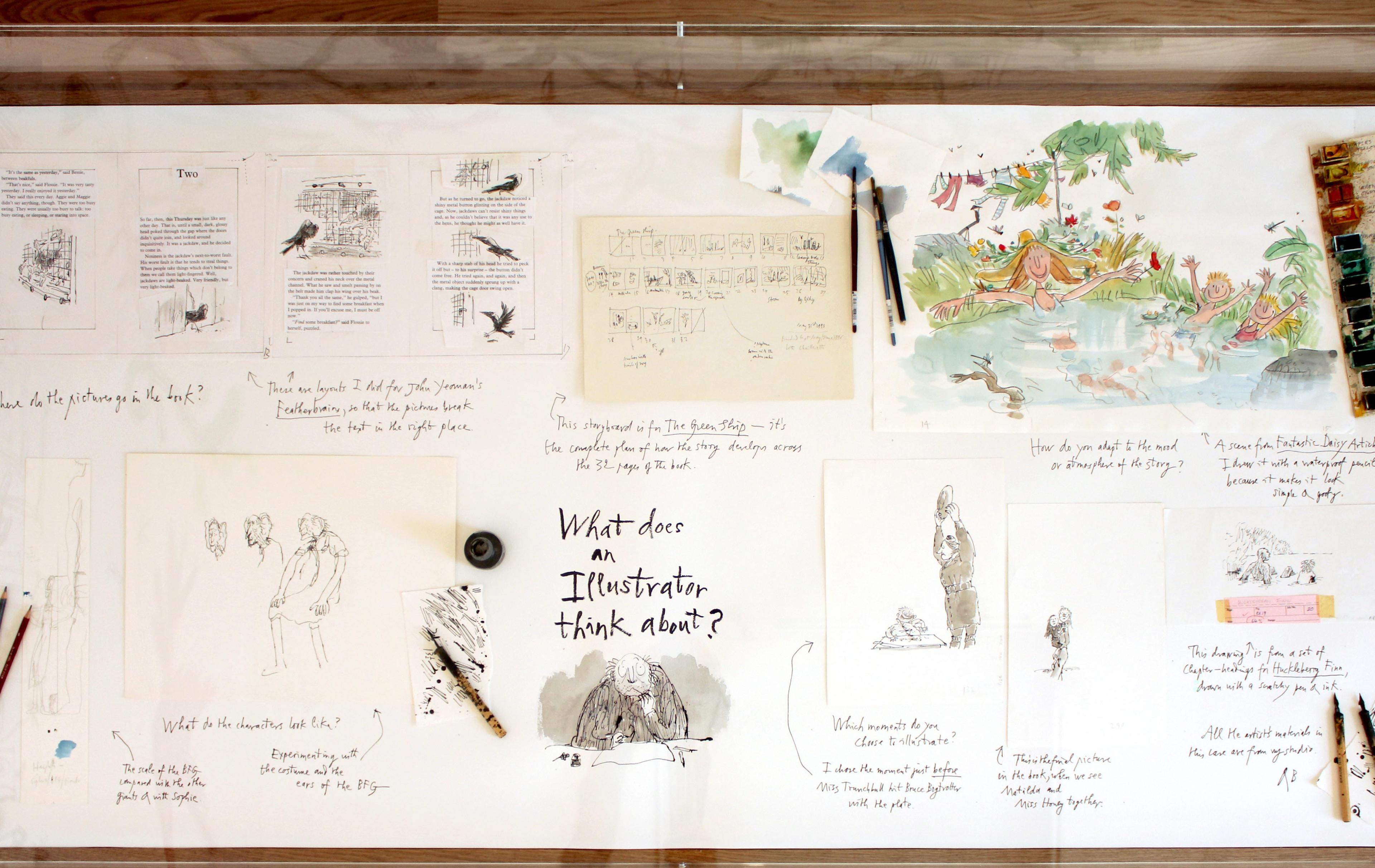 Ariel view of illustrations and some art tools in a display case.