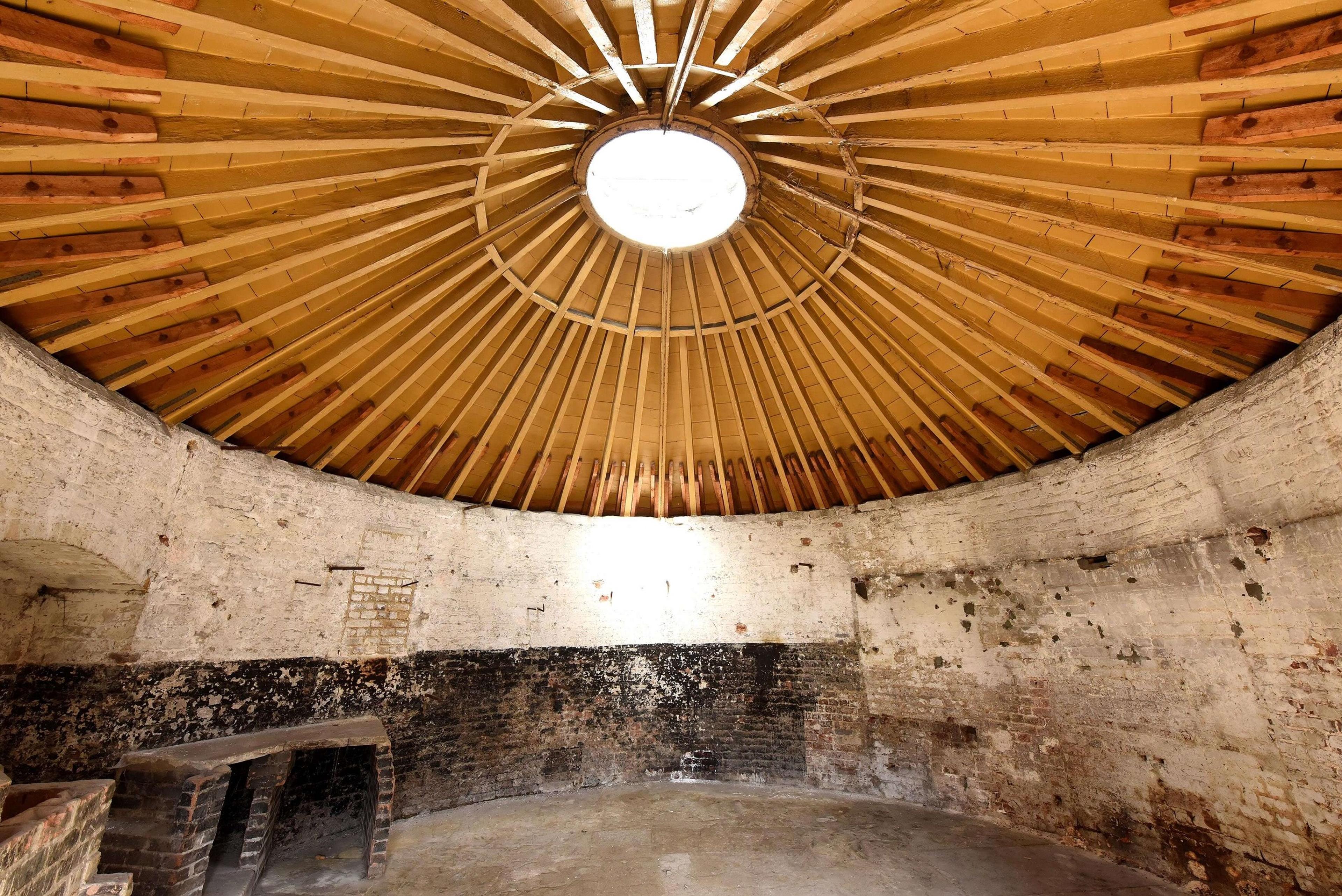 Interior of a one-storey round brick building with a wooden roof with a lantern in the centre