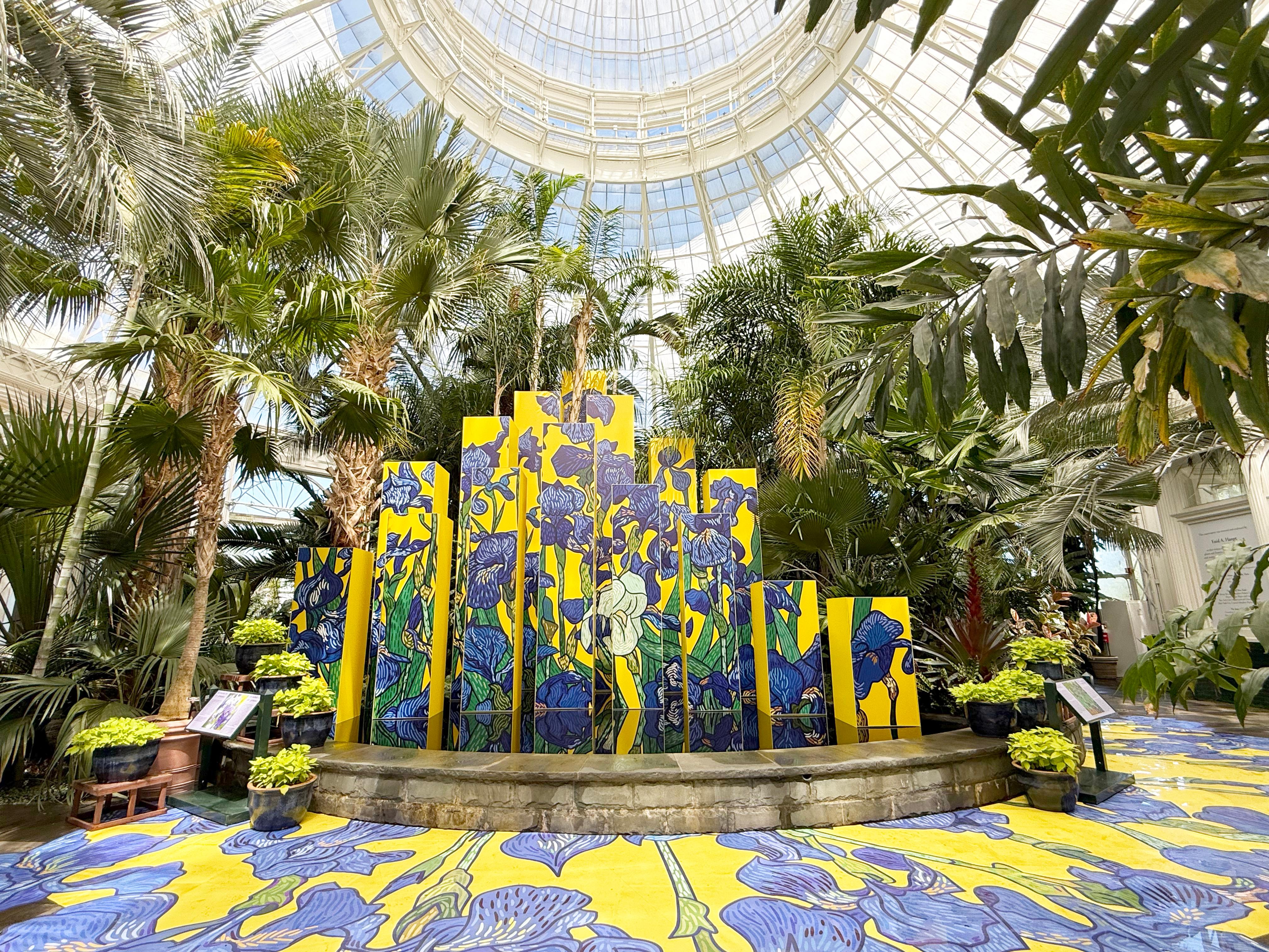 A colourful yellow and blue patterned sculpture sits within a large conservatory space.
