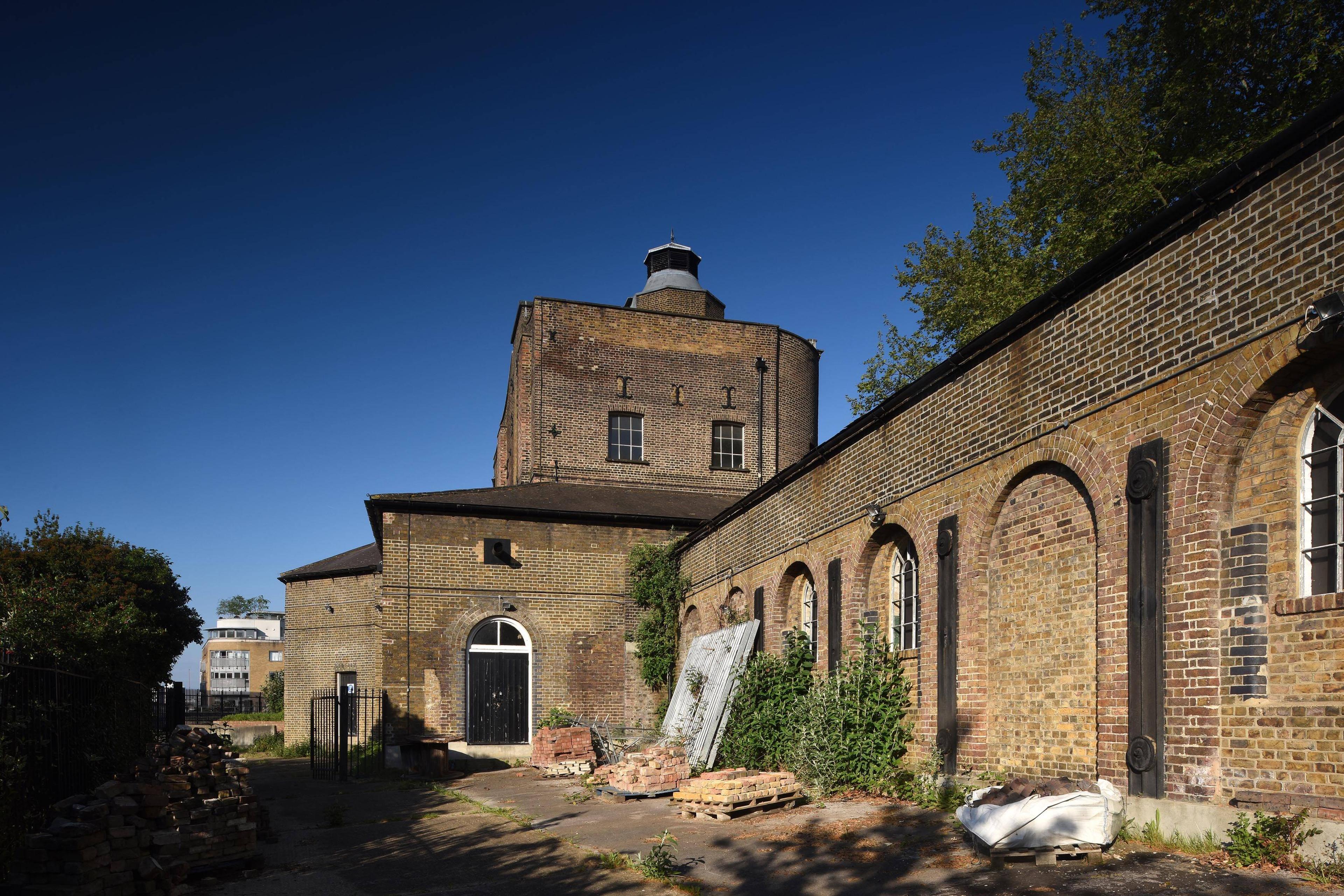 Photograph of a large derelict brick building with a blue sky behind it.