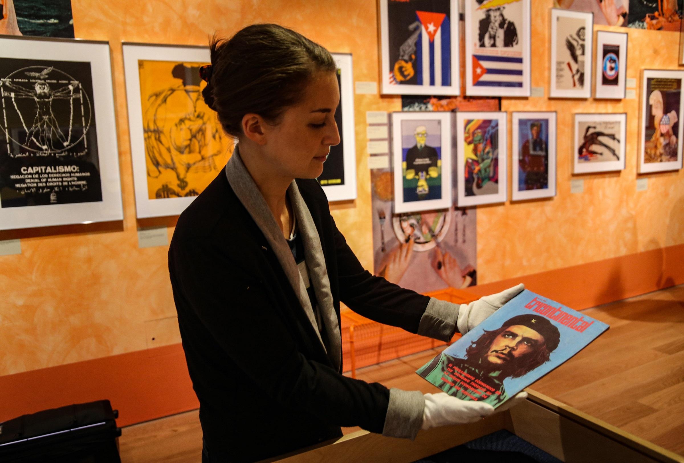 Photograph of person in a gallery wearing white gloves to hold a magazine
