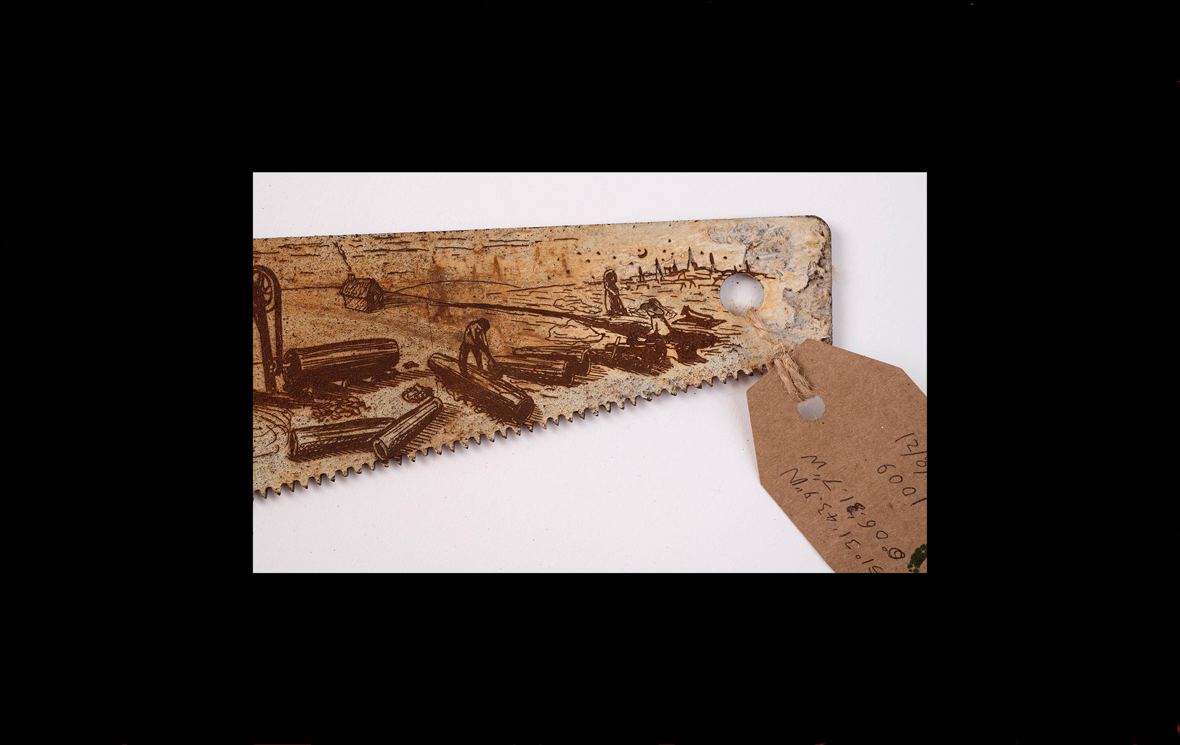 Rusted saw blade with etched design of people digging a trench to lay pipes with a cityscape in the background