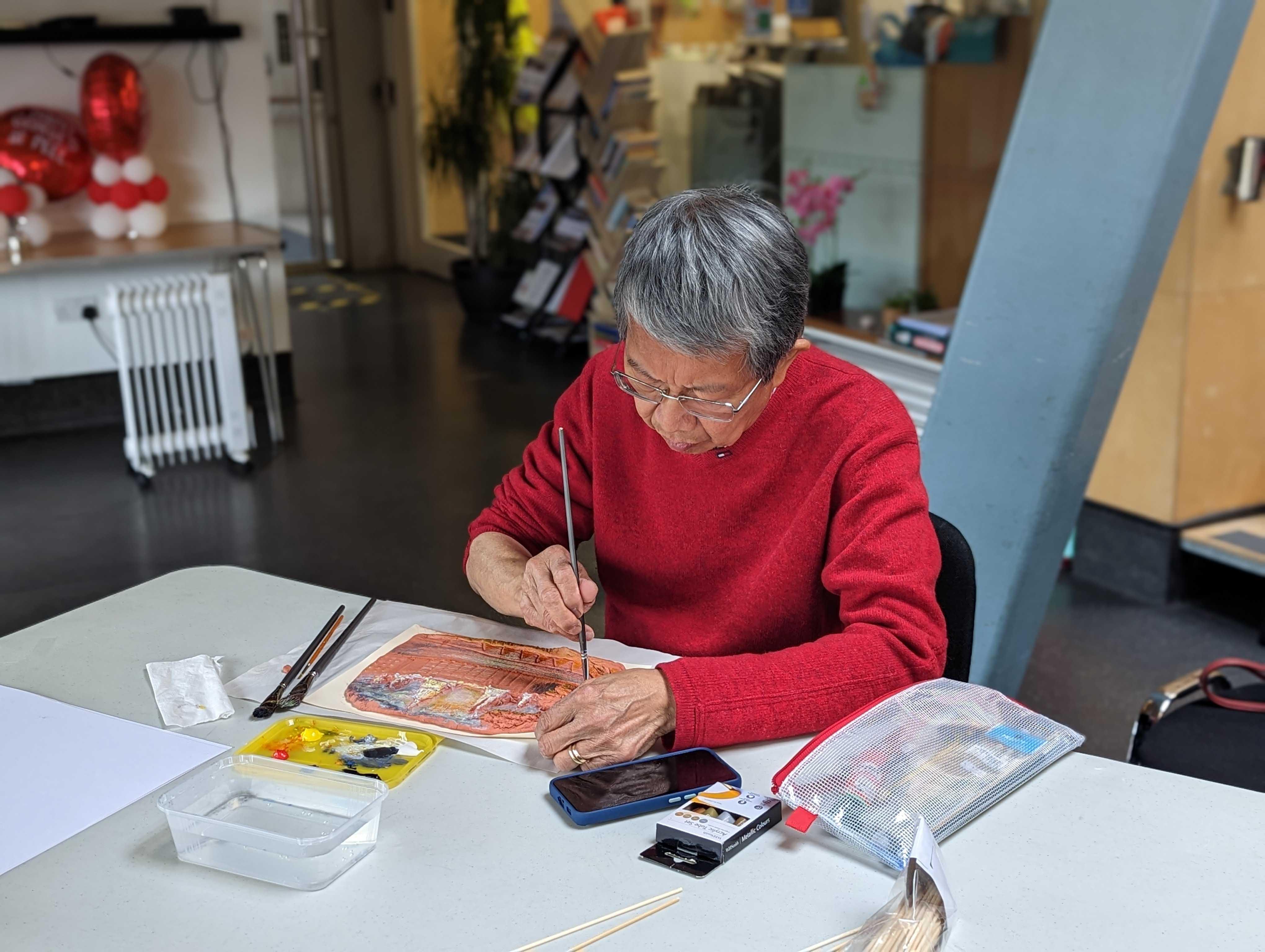 Person at a table painting a clay slab.