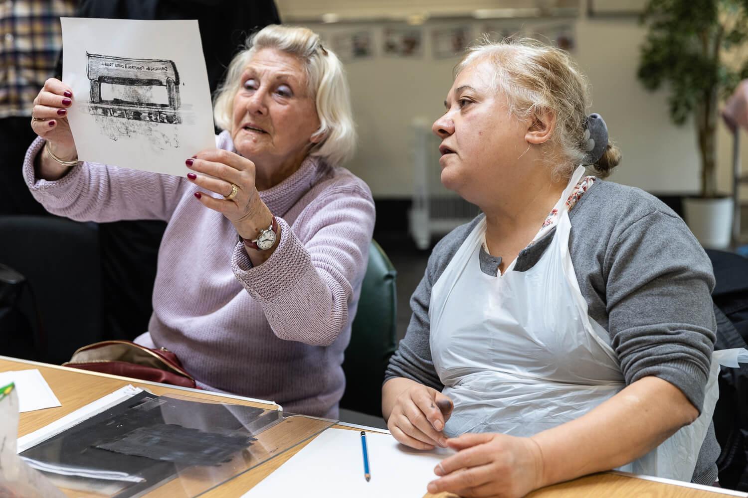 Photograph of two people looking at a print
