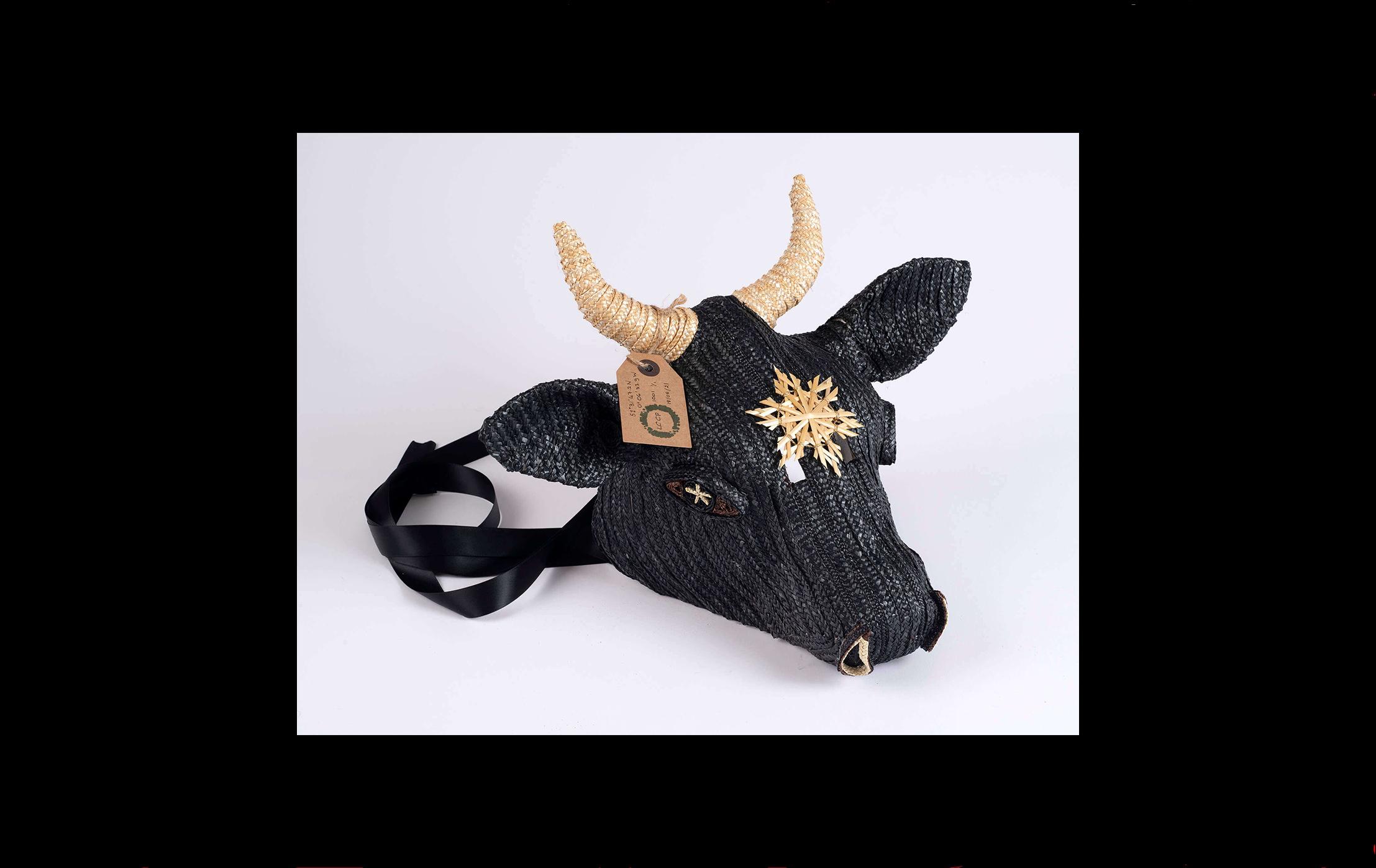 Photograph of a cow's head made with black straw and with a yellow straw woven star on its forehead